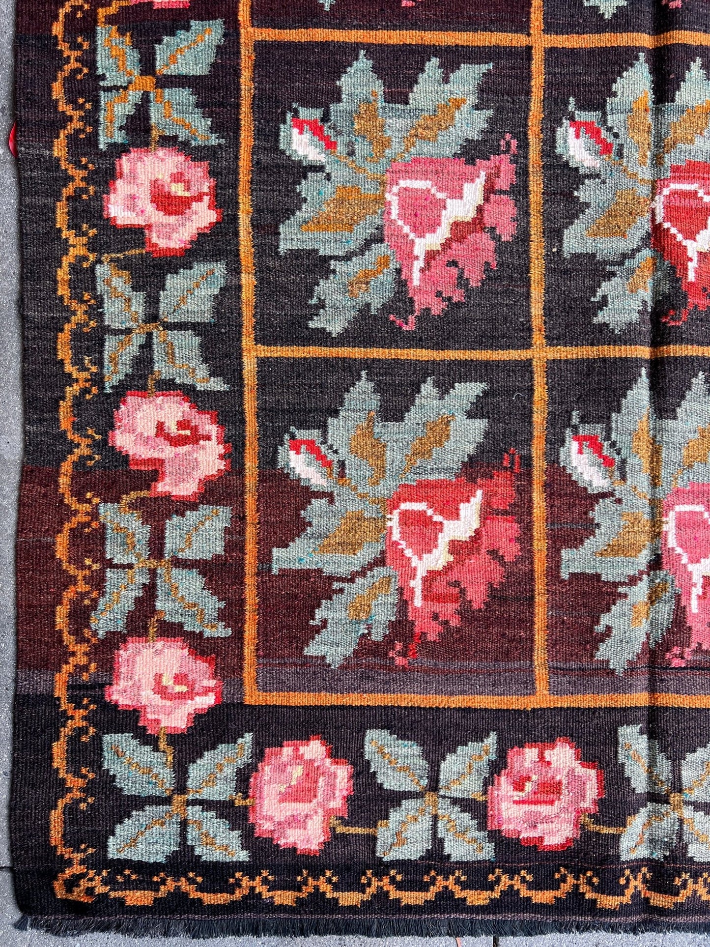 Vintage Moldovan Rose Kilim Rug from the 1950s, featuring a bold black ground with vibrant pink rose motifs and orange lines woven throughout. Handwoven with care, this flatweave rug adds unique character and style to living rooms, bedrooms, nurseries, kitchens, or dining areas. Free shipping included.