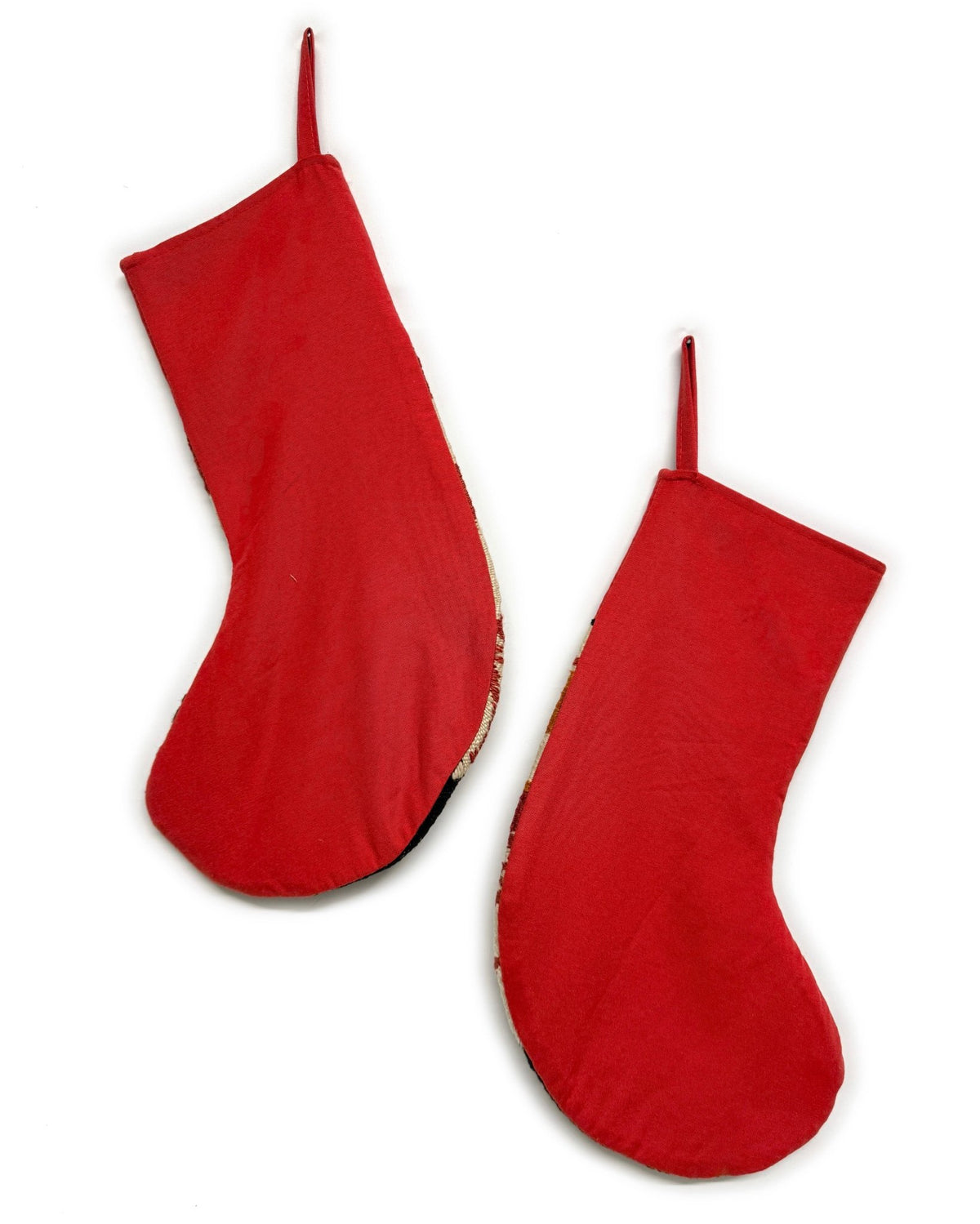 Two Christmas stockings with a Southwestern pattern, featuring red cuffs and hangers, a cream body, and geometric designs in red, brown, and black. Made from vintage wool Turkish rugs.