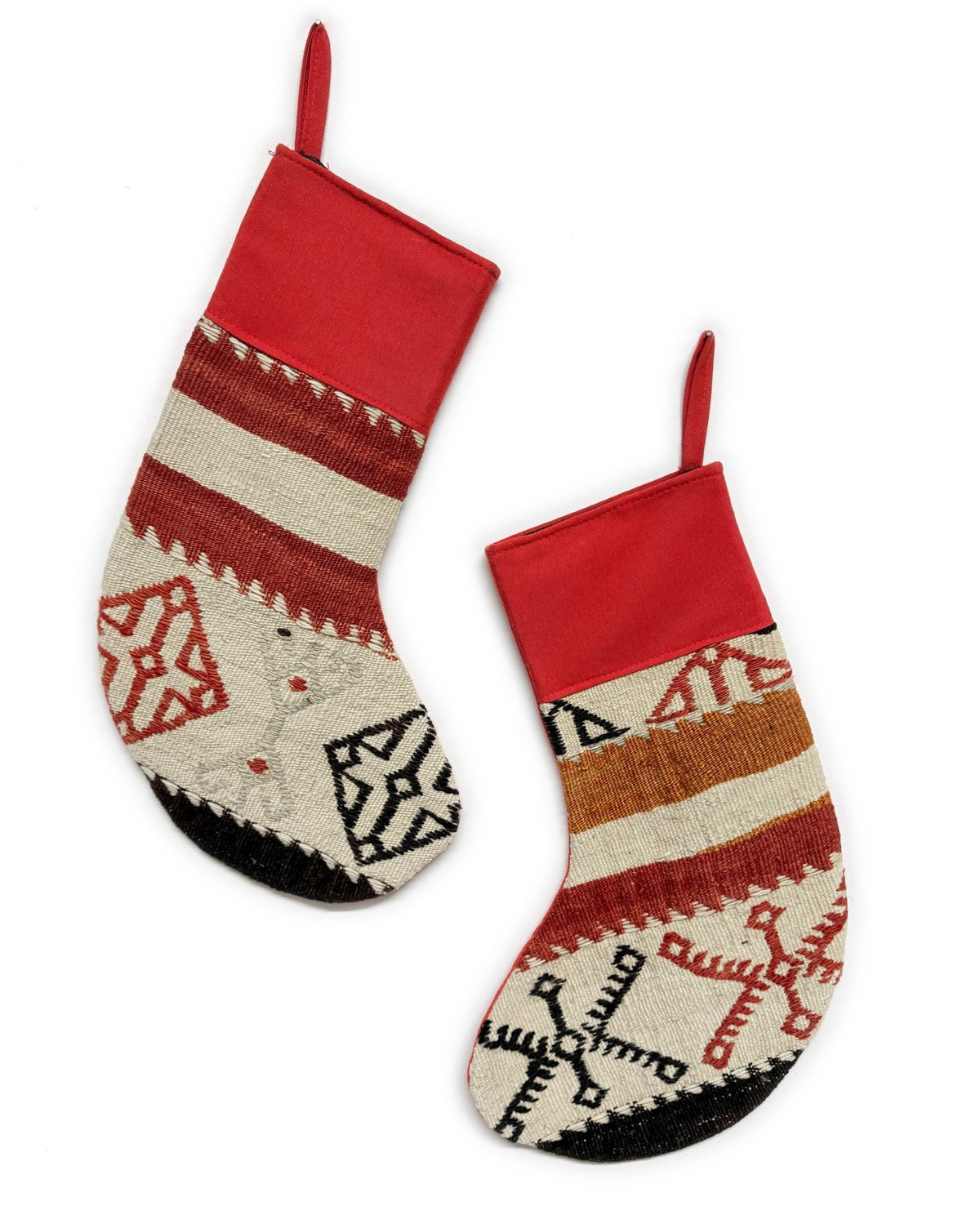 Two Christmas stockings with a Southwestern pattern, featuring red cuffs and hangers, a cream body, and geometric designs in red, brown, and black. Made from vintage wool Turkish rugs.