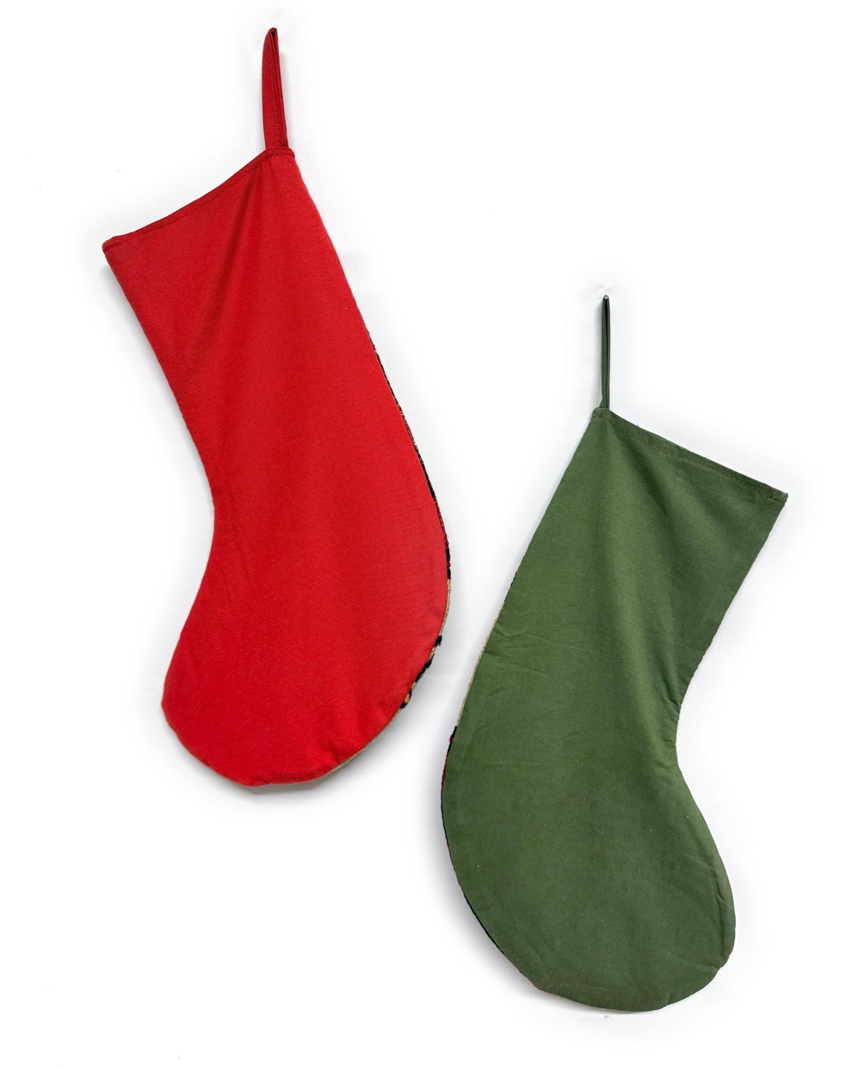 Two Christmas stockings with a Southwestern pattern, featuring red cuffs and hangers, a cream body, and geometric designs in red, brown, and black. Made from vintage wool Turkish rugs.