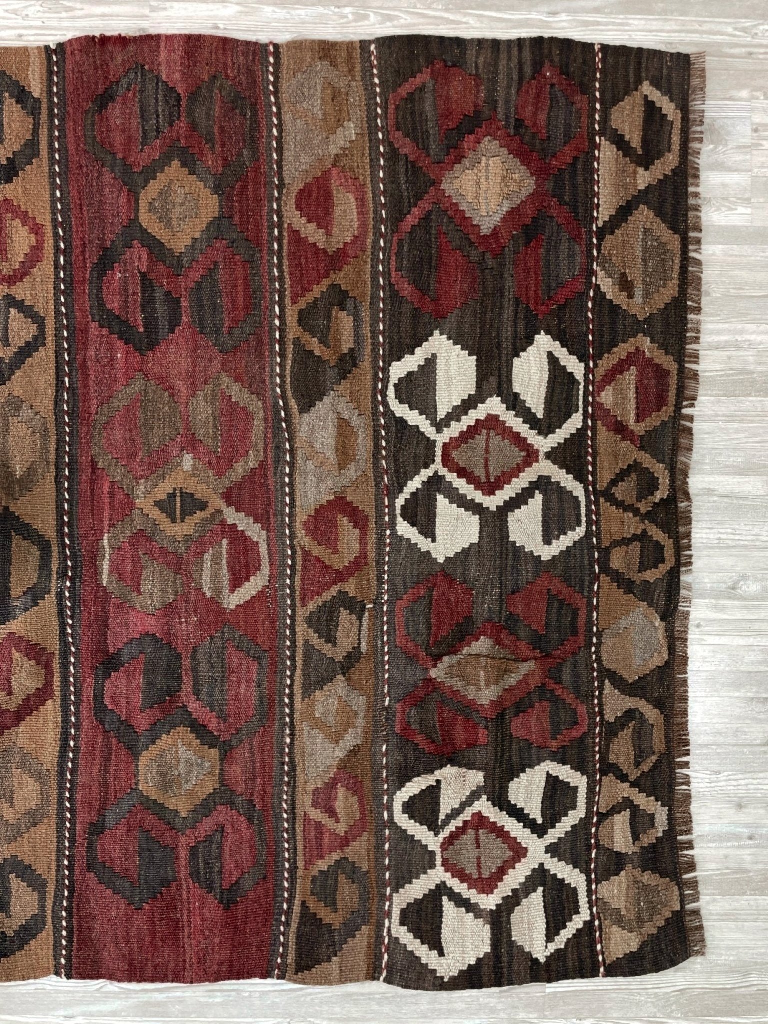 Vintage Eastern Turkish Kars kilim rug with horizontal tribal bands, hooked diamond motifs, and geometric symbols in madder red, walnut brown, 5x7.