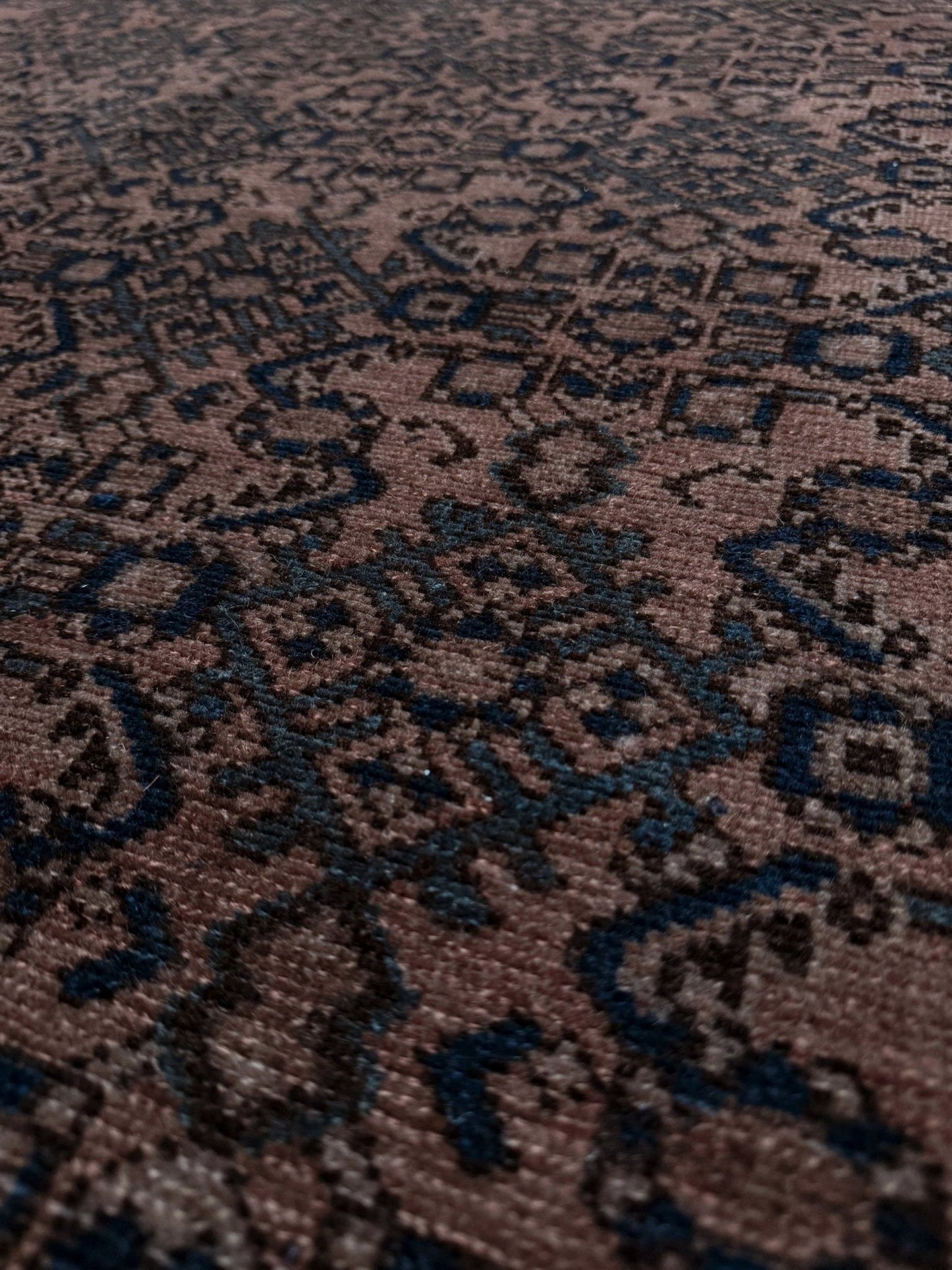 Close-up of a patterned rug with intricate designs. Vintage Persian Malayer overdyed rug in espresso brown with tonal geometric pattern, distressed handmade wool area rug 5x7 from Indigo Rugs Burlingame Bay Area.
