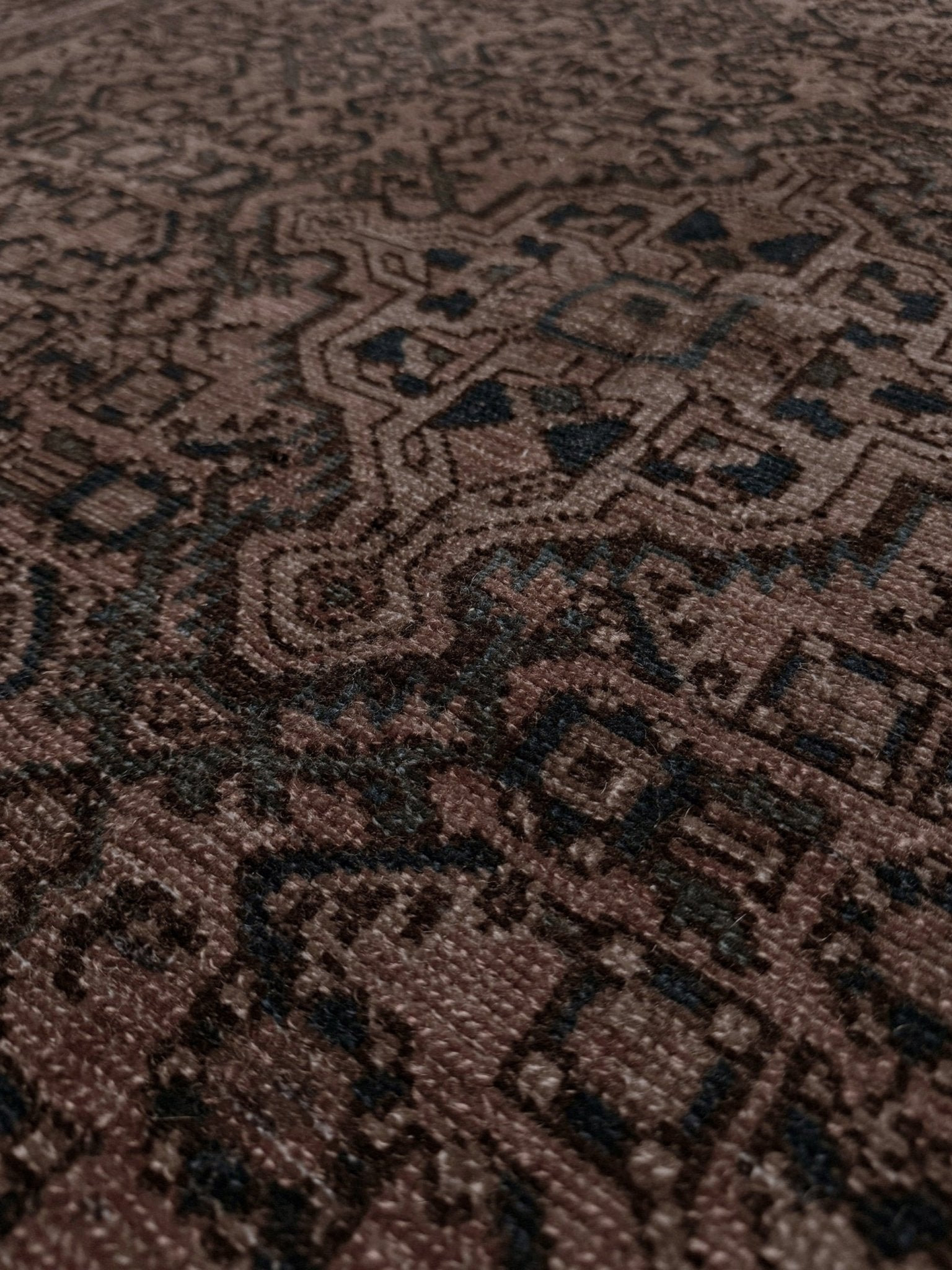 Close-up of a brown patterned rug with intricate designs. Vintage Persian Malayer overdyed rug in espresso brown with tonal geometric pattern, distressed handmade wool area rug 5x7 from Indigo Rugs Burlingame Bay Area.