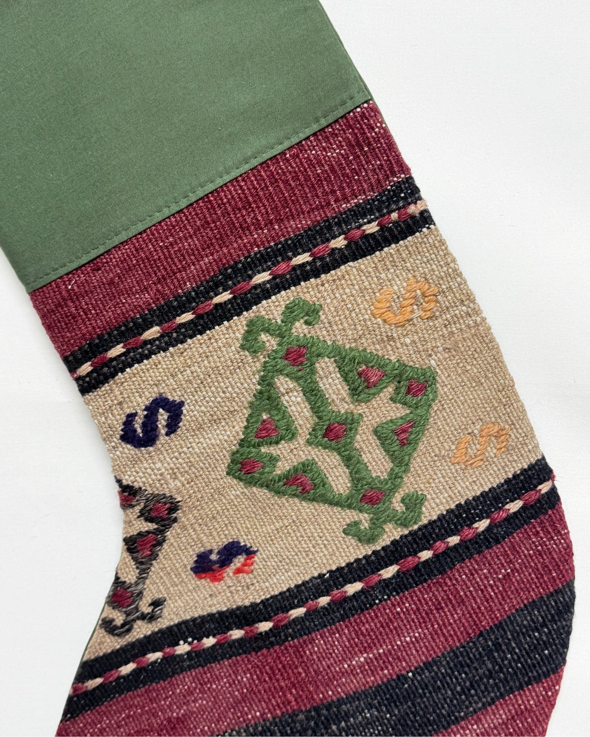 Two Christmas stockings with a Southwestern pattern, featuring red cuffs and hangers, a cream body, and geometric designs in red, brown, and black. Made from vintage wool Turkish rugs.