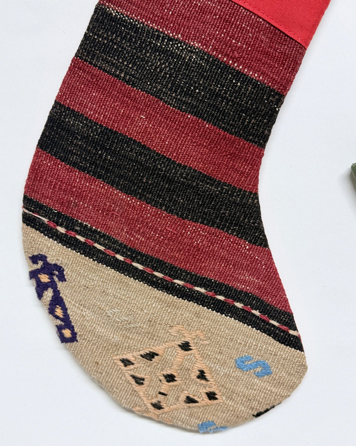 Two Christmas stockings with a Southwestern pattern, featuring red cuffs and hangers, a cream body, and geometric designs in red, brown, and black. Made from vintage wool Turkish rugs.