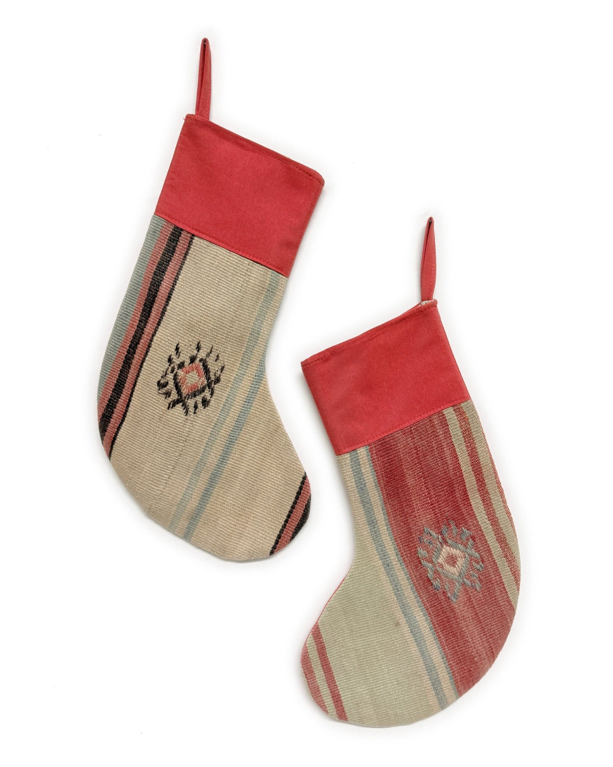 Two Christmas stockings with a rustic Southwestern pattern, featuring a red velvet cuff and hanging loops, on a solid white background.