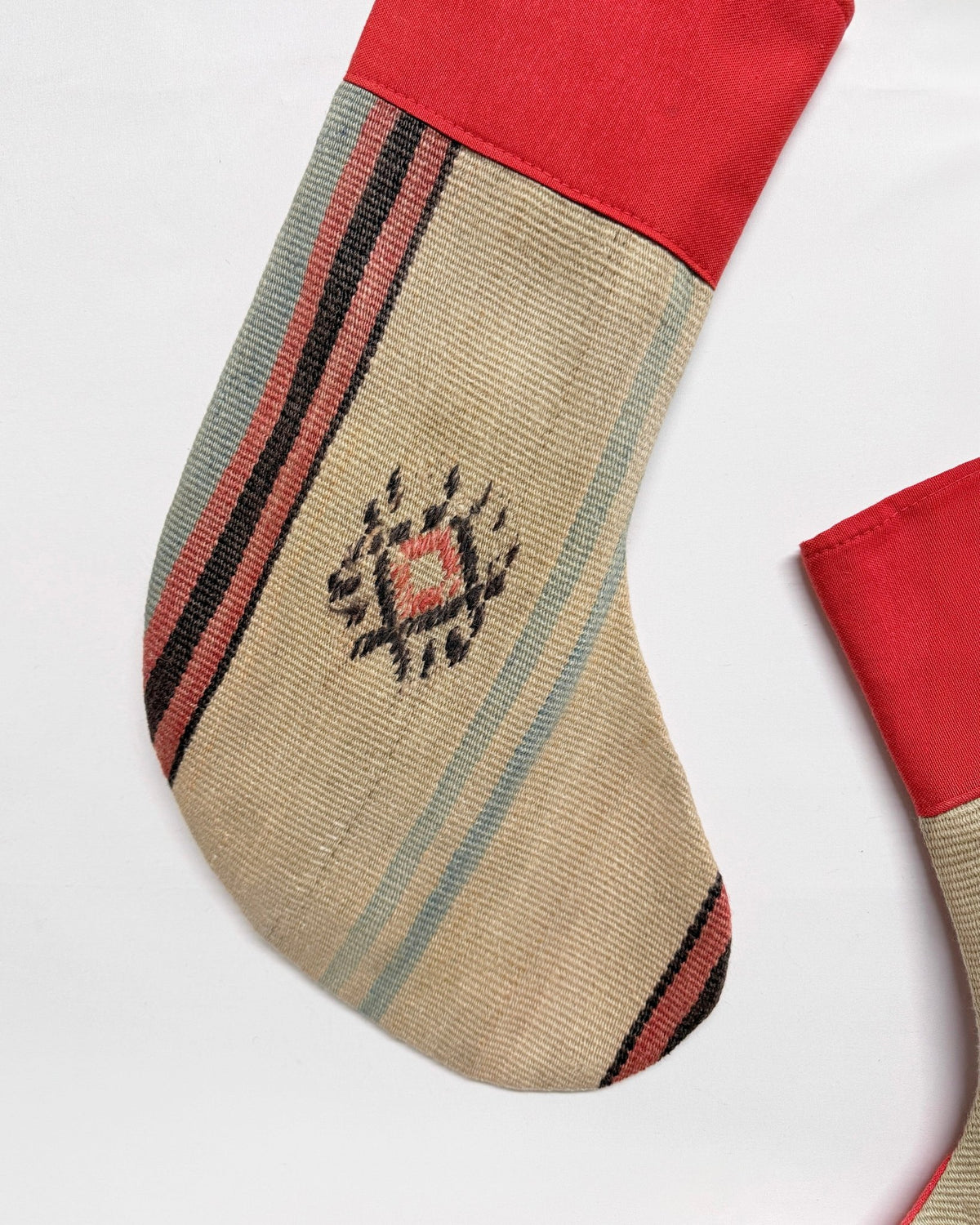 Two Christmas stockings with a rustic Southwestern pattern, featuring a red velvet cuff and hanging loops, on a solid white background.