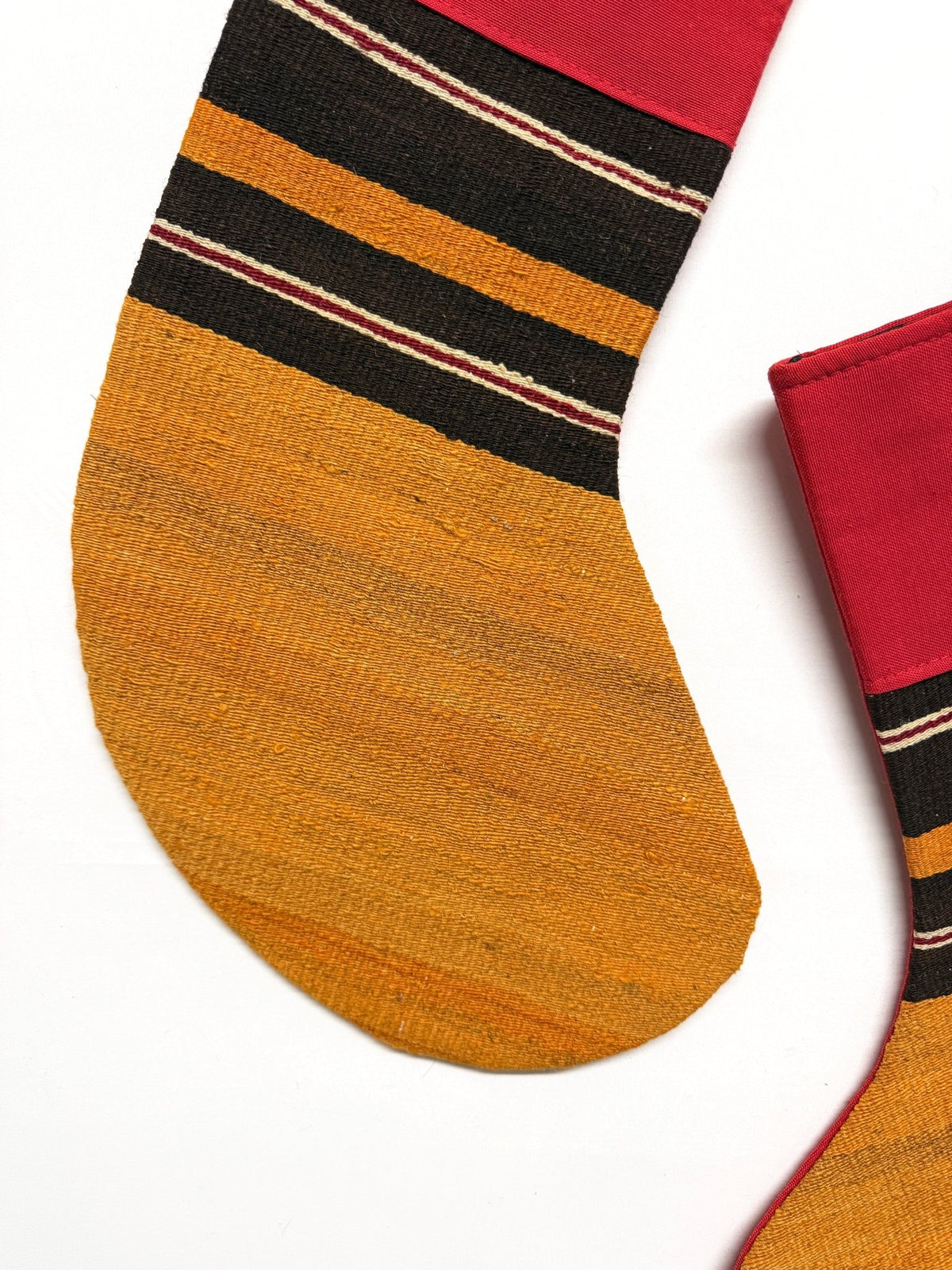 Two Christmas stockings with a striped pattern in red, black, and yellow, shown on a plain white background.