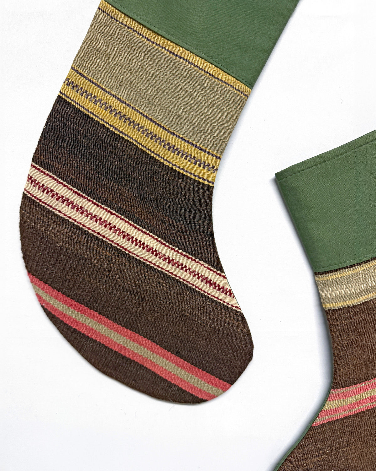 A close-up of a striped knit sock with an olive green cuff, featuring horizontal bands of brown, beige, yellow, and pink on a white background.