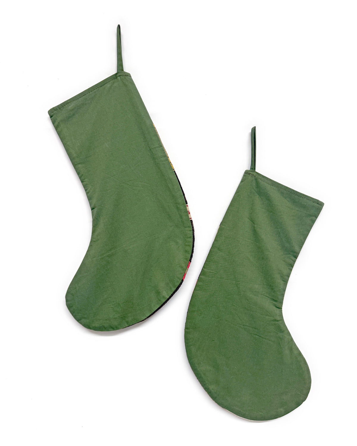 Two olive green fabric stockings hanging against a plain white background.