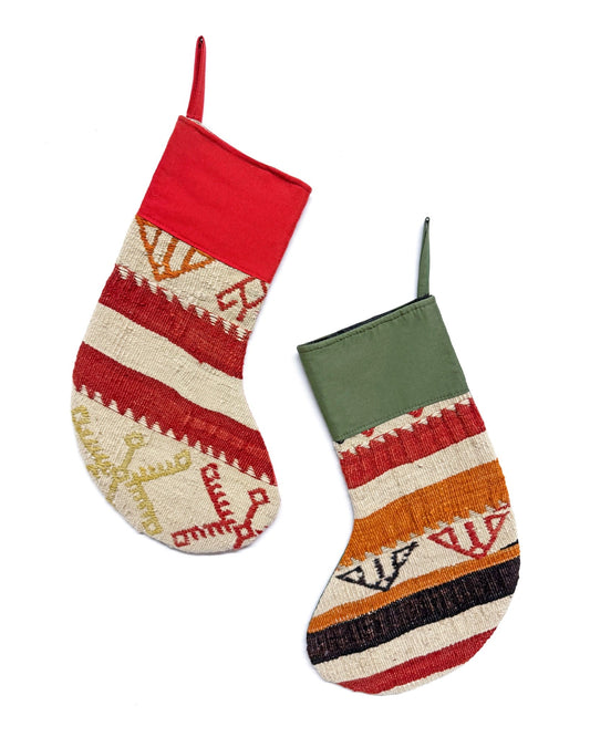 Two handwoven Christmas stockings with Southwestern geometric patterns, displayed on a clean white background. One stocking features a red cuff and red, orange, and beige stripes with a gold anchor motif.