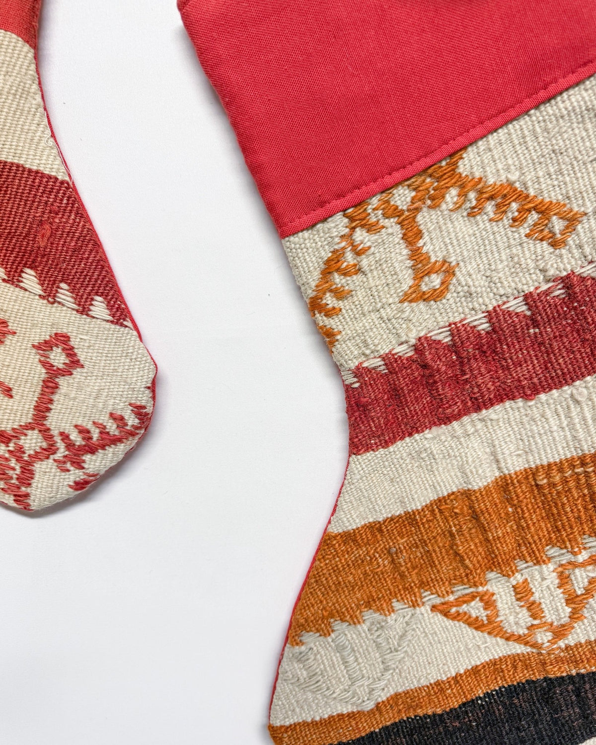 Two handwoven Christmas stockings with Southwestern geometric patterns, displayed on a clean white background. One stocking features a red cuff and red, orange, and beige stripes with a gold anchor motif.