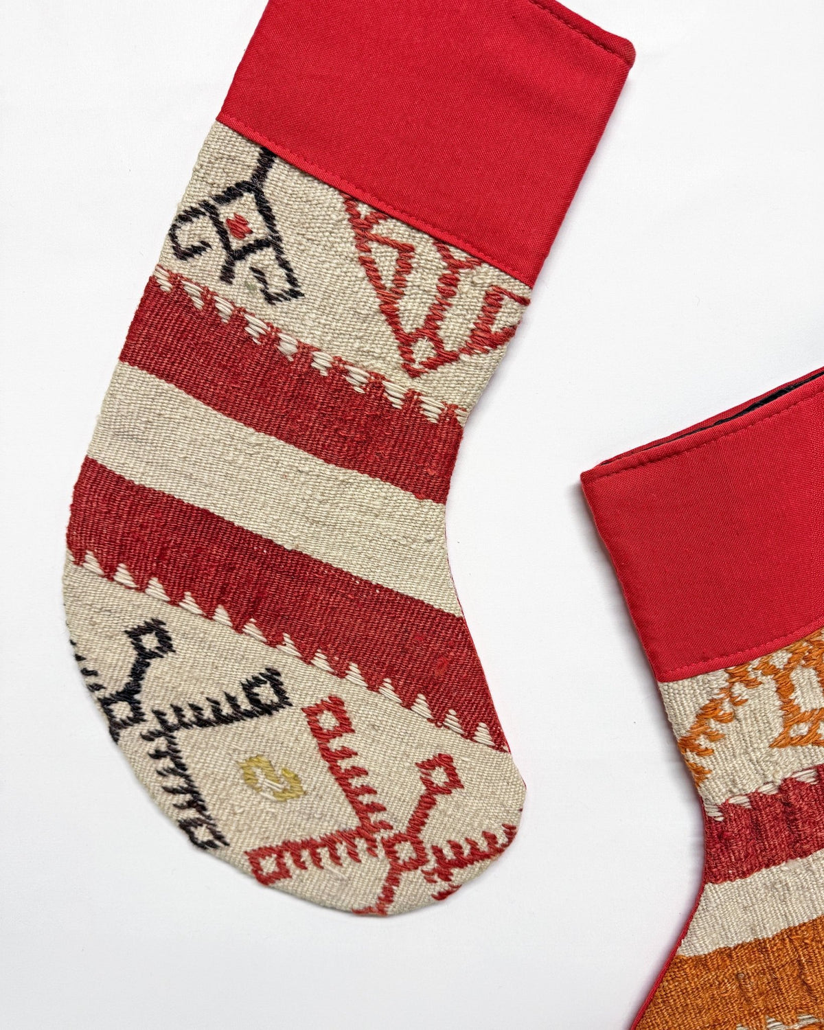 Two handwoven Christmas stockings with Southwestern geometric patterns, displayed on a clean white background. One stocking features a red cuff and red, orange, and beige stripes with a gold anchor motif.