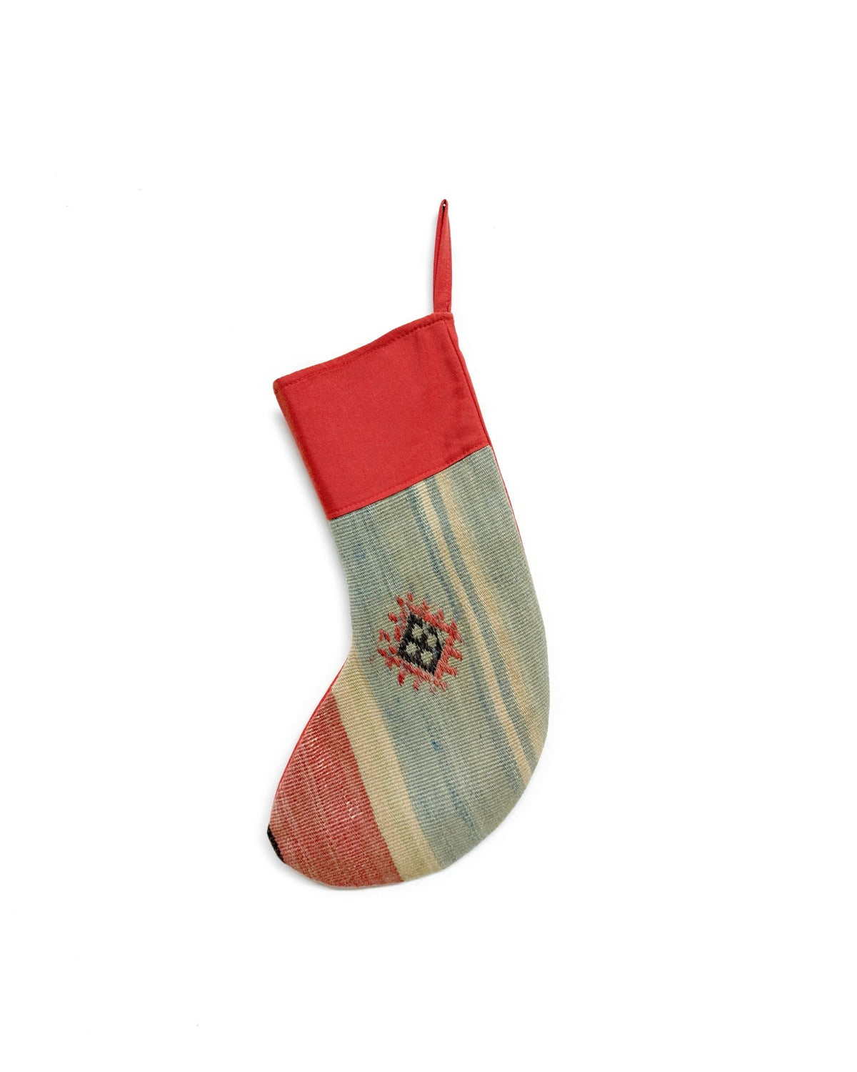 A Kilim handmade Christmas stocking featuring a red cuff and hanging loop, with a body made from striped kilim fabric in sage green, beige, and rust red, accented by a small geometric woven motif.