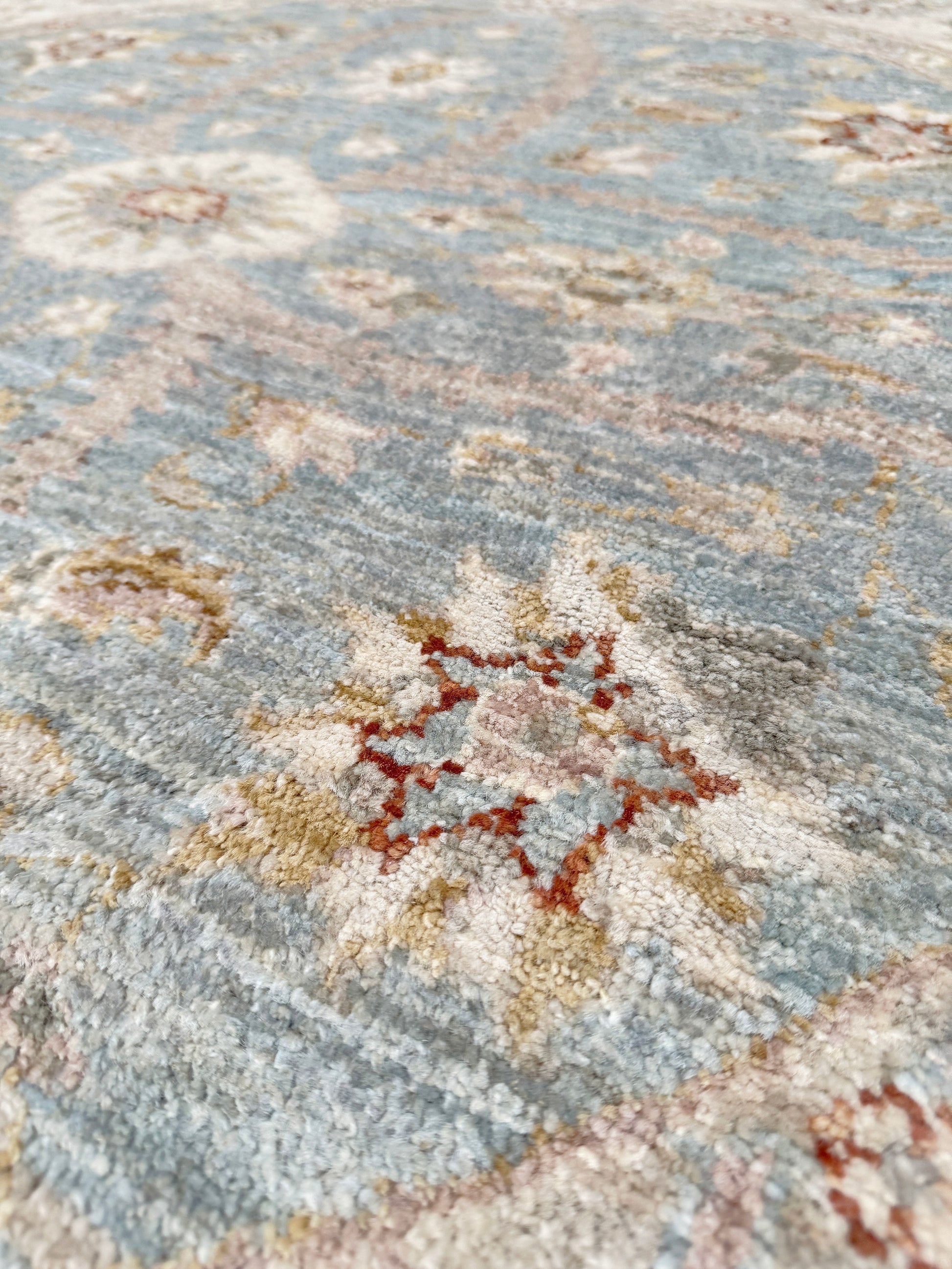 Pale blue round Turkish Oushak rug with soft colored floral details, handmade wool 5x5 round area rug from Indigo Rugs Burlingame Bay Area.