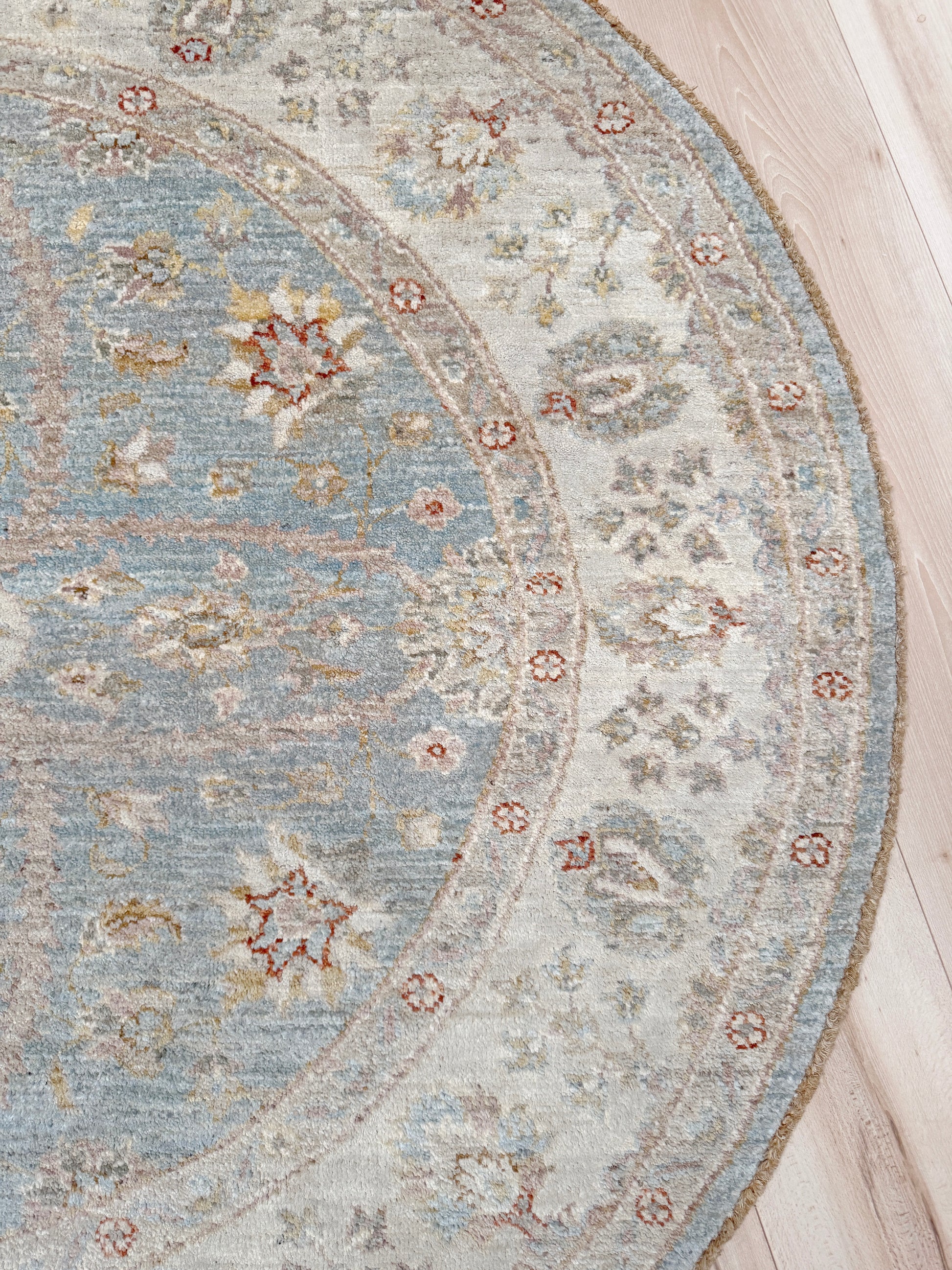 Pale blue round Turkish Oushak rug with soft colored floral details, handmade wool 5x5 round area rug from Indigo Rugs Burlingame Bay Area.