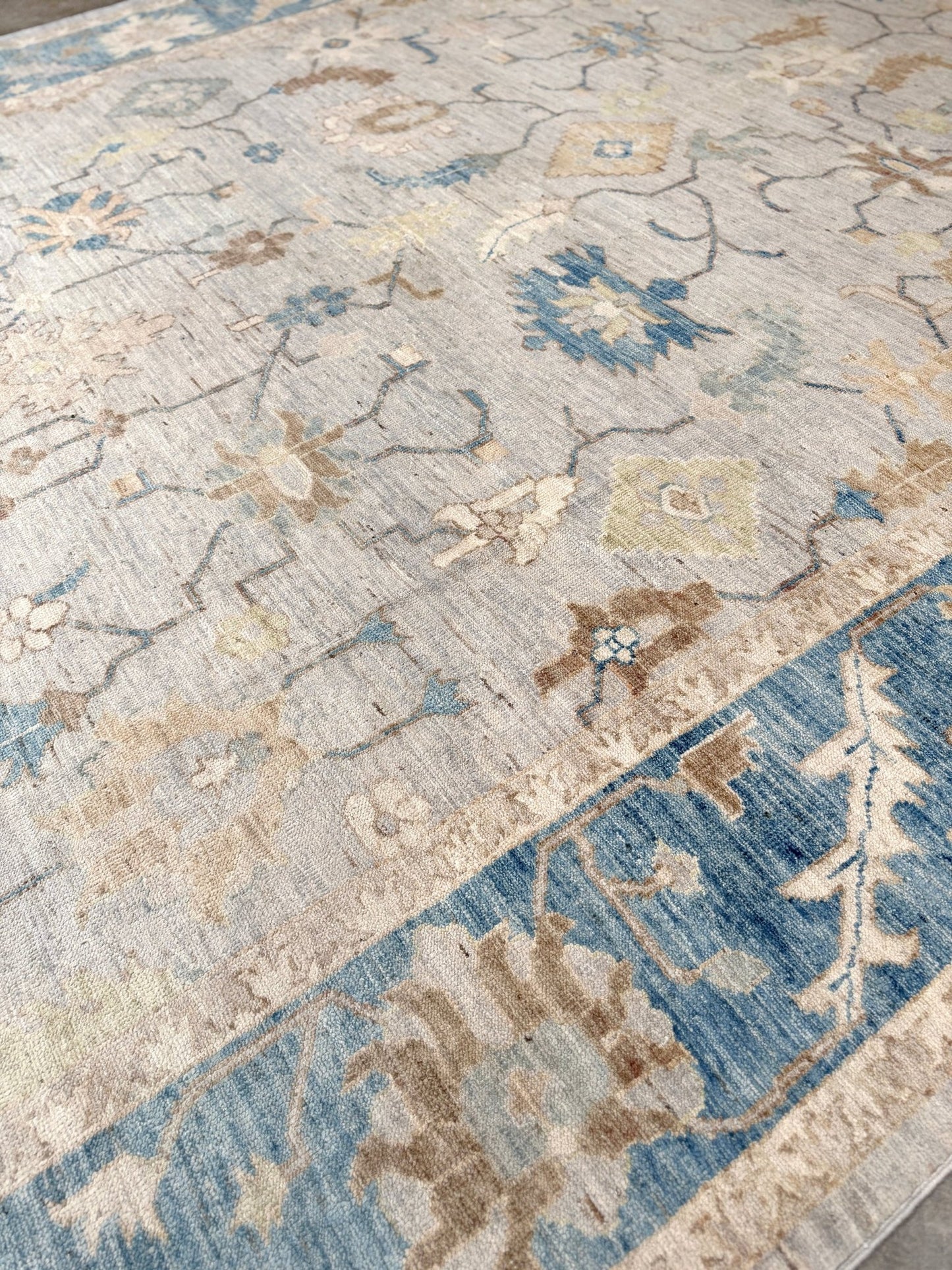 Brand new Turkish Oushak rug with soft ivory field, pale blue border, faded floral motifs, handmade wool area rug 9x12 from Indigo Rugs Burlingame Bay Area.