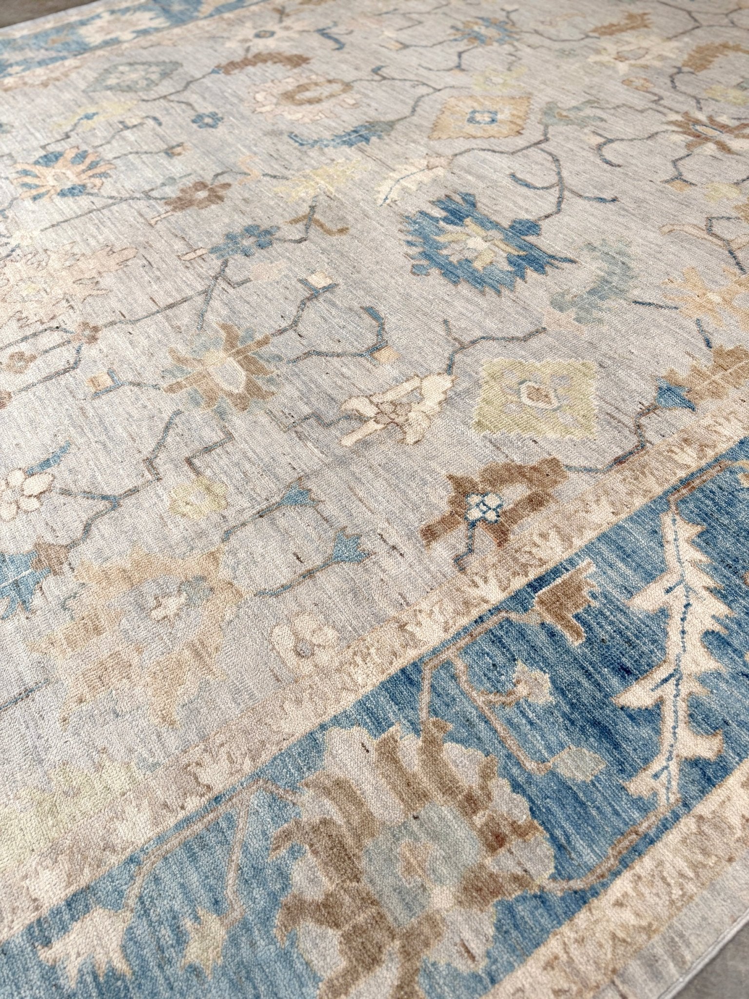 Brand new Turkish Oushak rug with soft ivory field, pale blue border, faded floral motifs, handmade wool area rug 9x12 from Indigo Rugs Burlingame Bay Area.