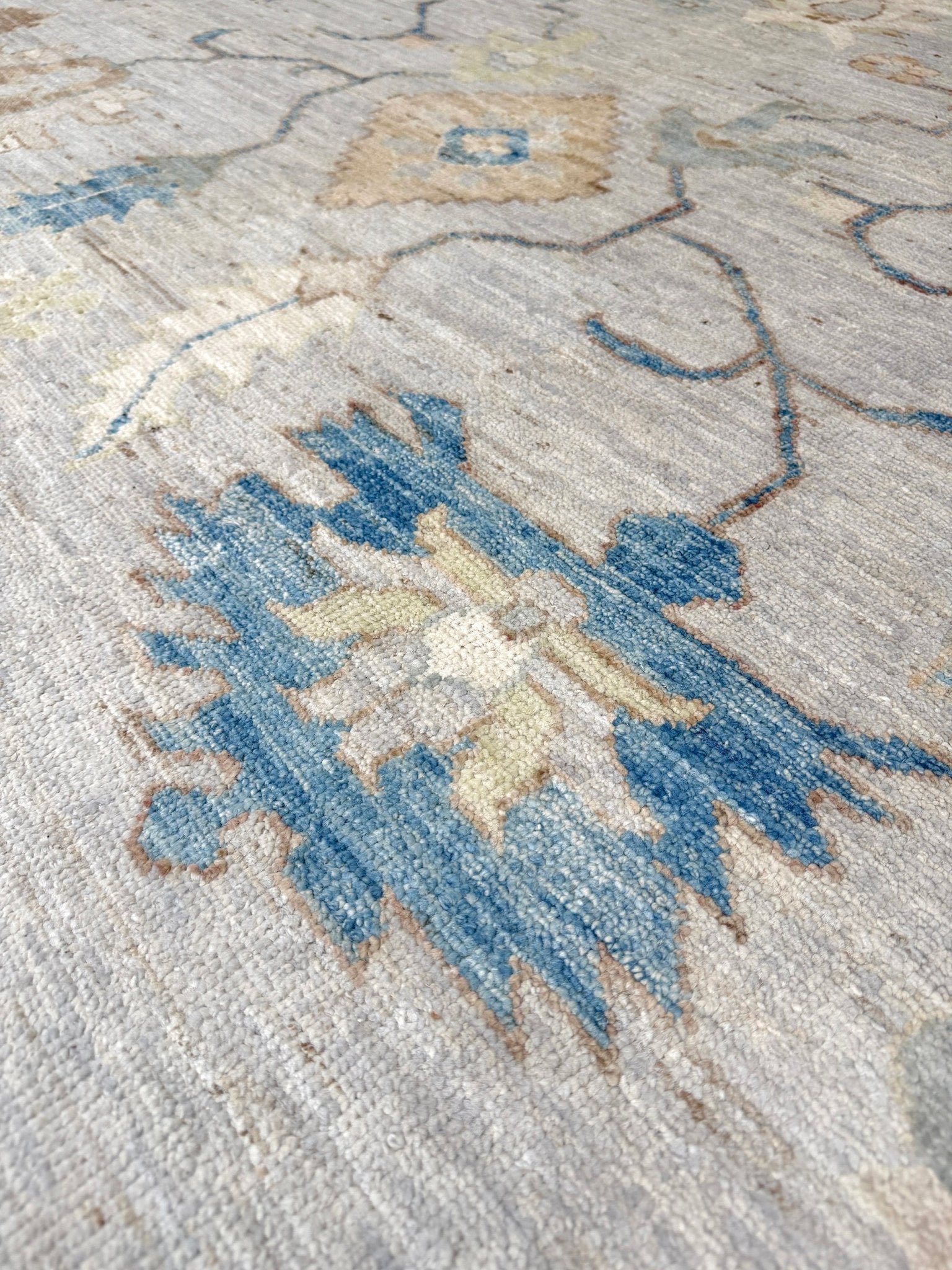Brand new Turkish Oushak rug with soft ivory field, pale blue border, faded floral motifs, handmade wool area rug 9x12 from Indigo Rugs Burlingame Bay Area.