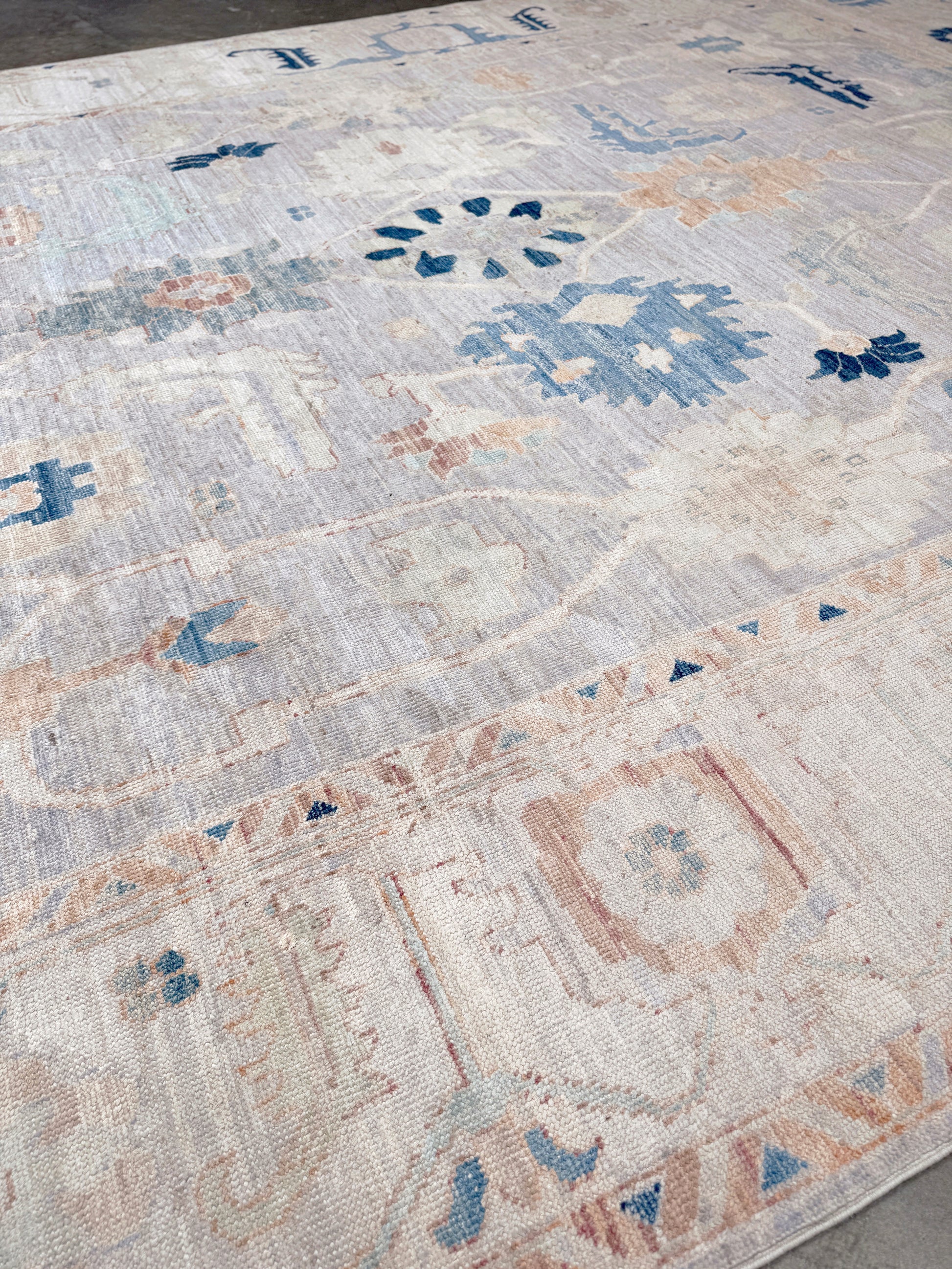 Brand new Turkish Oushak rug with pale blue field, subtle lilac undertones, soft ivory border, faded blue and peach beige accents, handmade wool area rug 9x12 from Indigo Rugs Burlingame Bay Area.