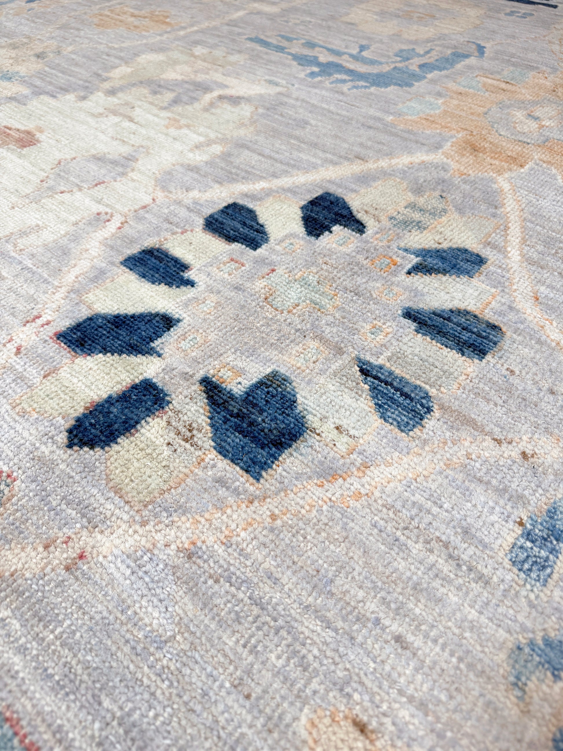 Brand new Turkish Oushak rug with pale blue field, subtle lilac undertones, soft ivory border, faded blue and peach beige accents, handmade wool area rug 9x12 from Indigo Rugs Burlingame Bay Area.