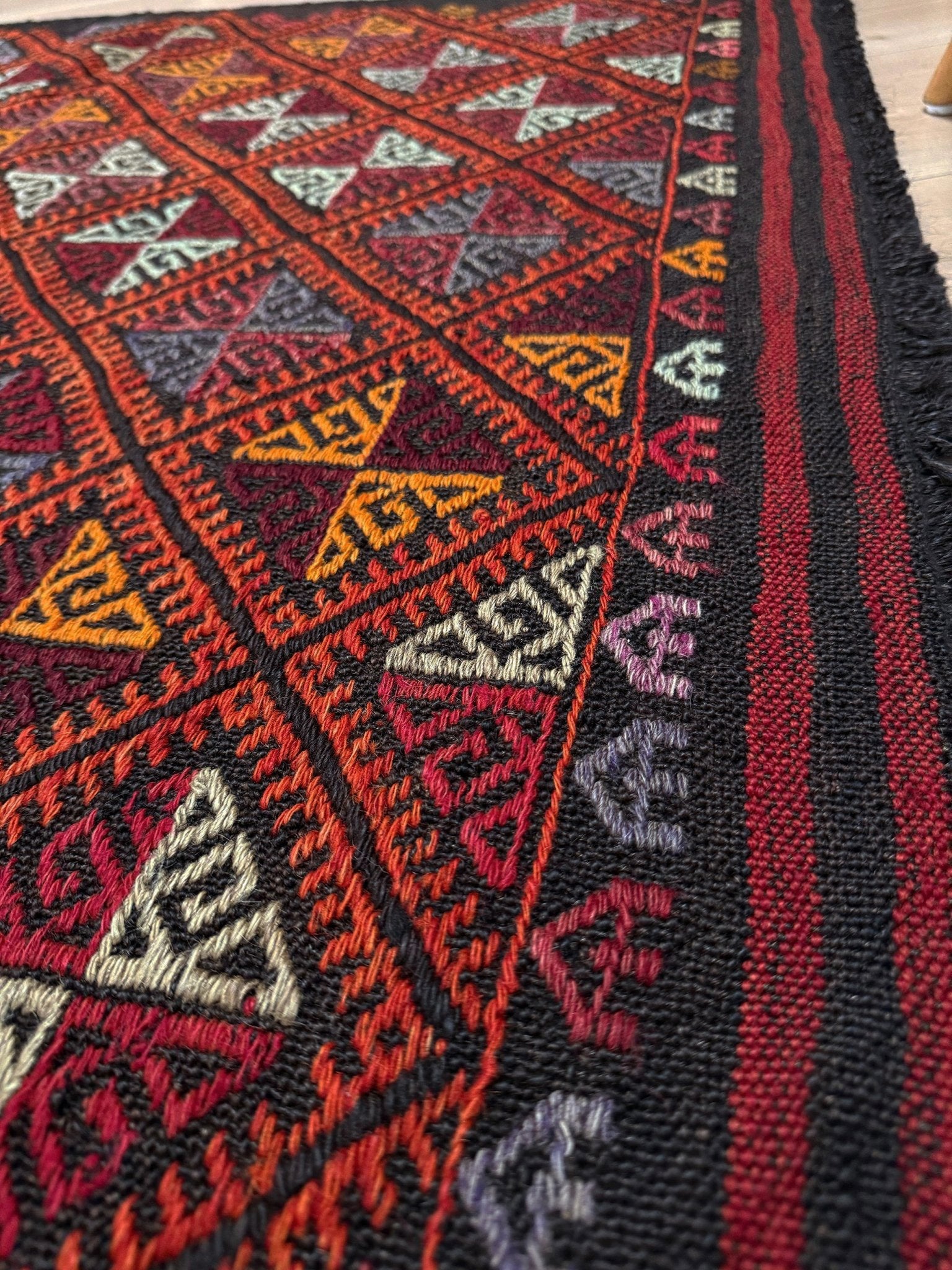Close-up of a patterned rug with geometric designs in red, black, and multicolor.