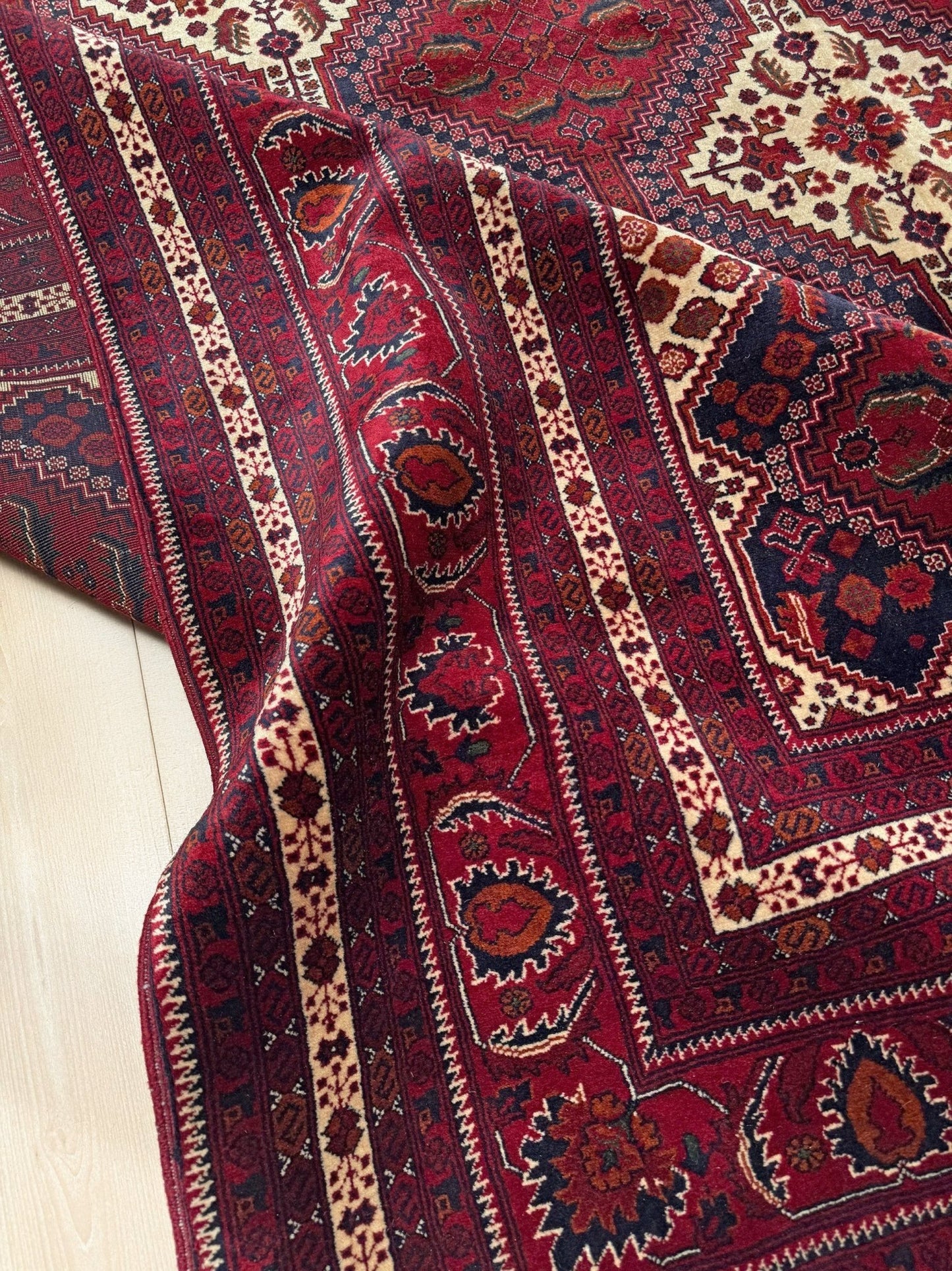 Deep crimson Khal Mohammadi Afghan rug with classic Turkmen gul medallions, dark navy border, ivory details, burgundy, terracotta, beige and forest green accents, handmade Merino wool 10x14 from Indigo Rugs Burlingame Bay Area.
