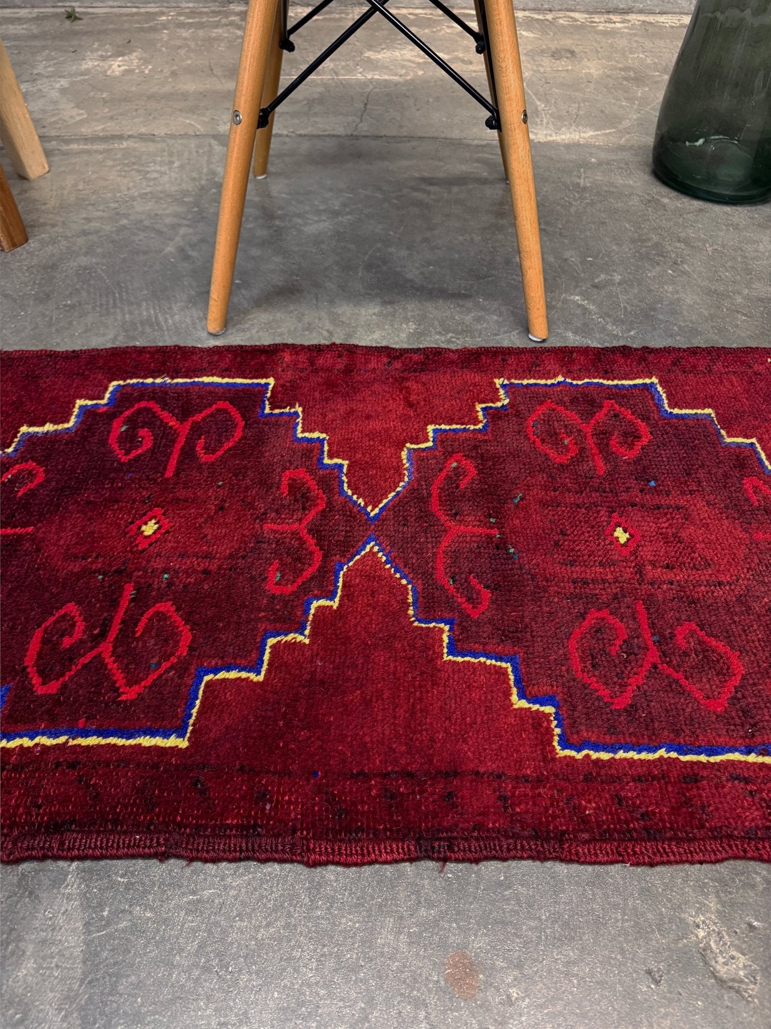 Vintage Turkish Yastik rug in deep cherry red with fuchsia tribal motifs, blue outlines, and yellow highlights. Hand-knotted wool, 20x43 inches. One-of-a-kind piece from Indigo Rugs, the best rug shop in the San Francisco Bay Area (Burlingame, CA). Free shipping included.