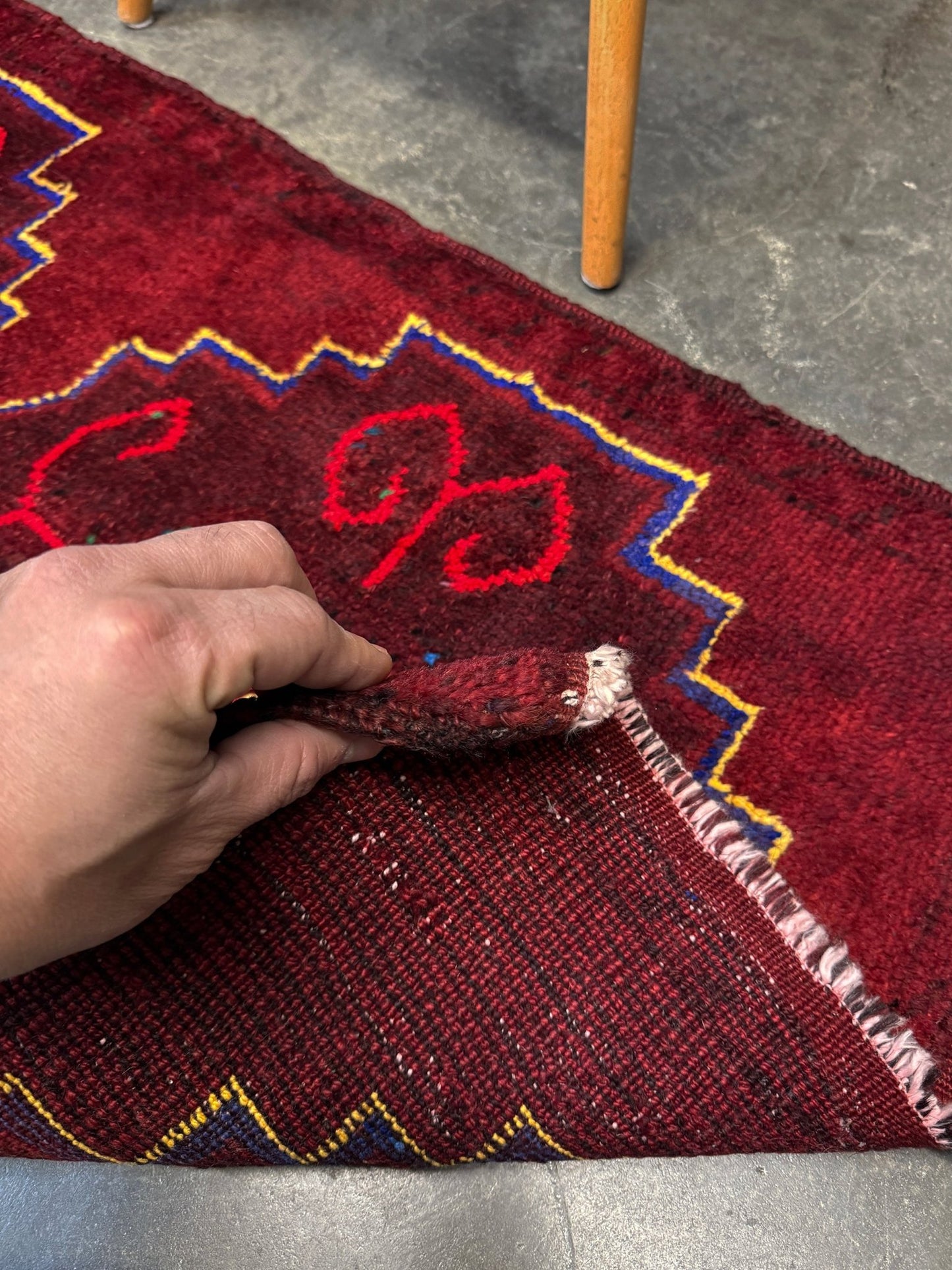 Vintage Turkish Yastik rug in deep cherry red with fuchsia hot pink tribal motifs, blue outlines, and yellow highlights. Hand-knotted wool, 20x43 inches. One-of-a-kind piece from Indigo Rugs, the best rug shop in the San Francisco Bay Area (Burlingame, CA). Free shipping included.