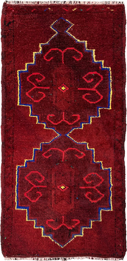 Vintage Turkish Yastik rug in deep cherry red with fuchsia tribal motifs, blue outlines, and yellow highlights. Hand-knotted wool, 20x43 inches. One-of-a-kind piece from Indigo Rugs, the best rug shop in the San Francisco Bay Area (Burlingame, CA). Free shipping included.