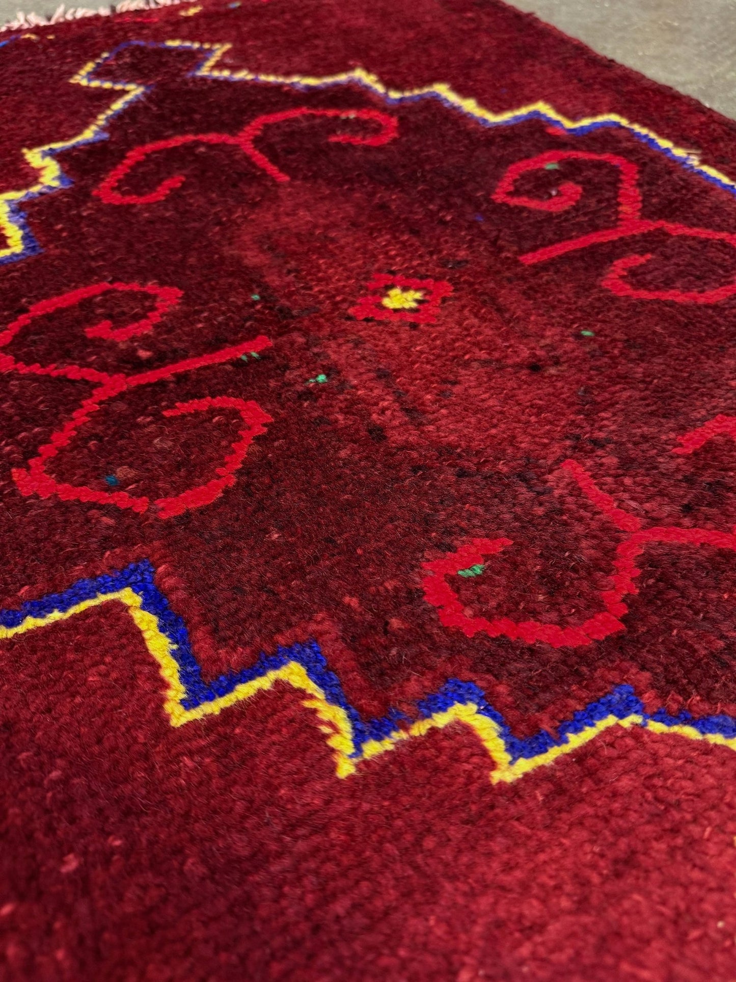 Vintage Turkish Yastik rug in deep cherry red with fuchsia hot pink tribal motifs, blue outlines, and yellow highlights. Hand-knotted wool, 20x43 inches. One-of-a-kind piece from Indigo Rugs, the best rug shop in the San Francisco Bay Area (Burlingame, CA). Free shipping included.