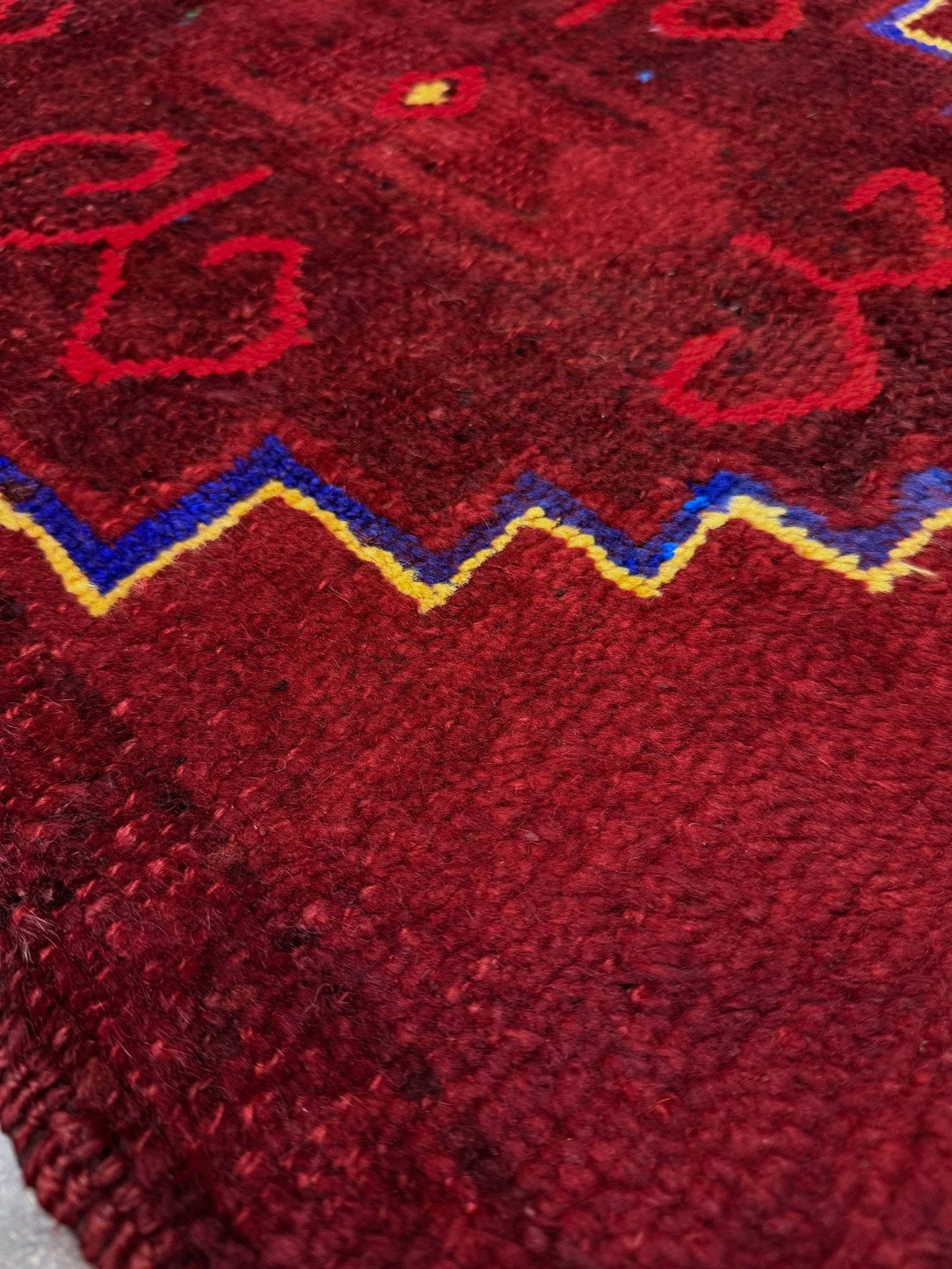 Vintage Turkish Yastik rug in deep cherry red with fuchsia tribal motifs, blue outlines, and yellow highlights. Hand-knotted wool, 20x43 inches. One-of-a-kind piece from Indigo Rugs, the best rug shop in the San Francisco Bay Area (Burlingame, CA). Free shipping included.