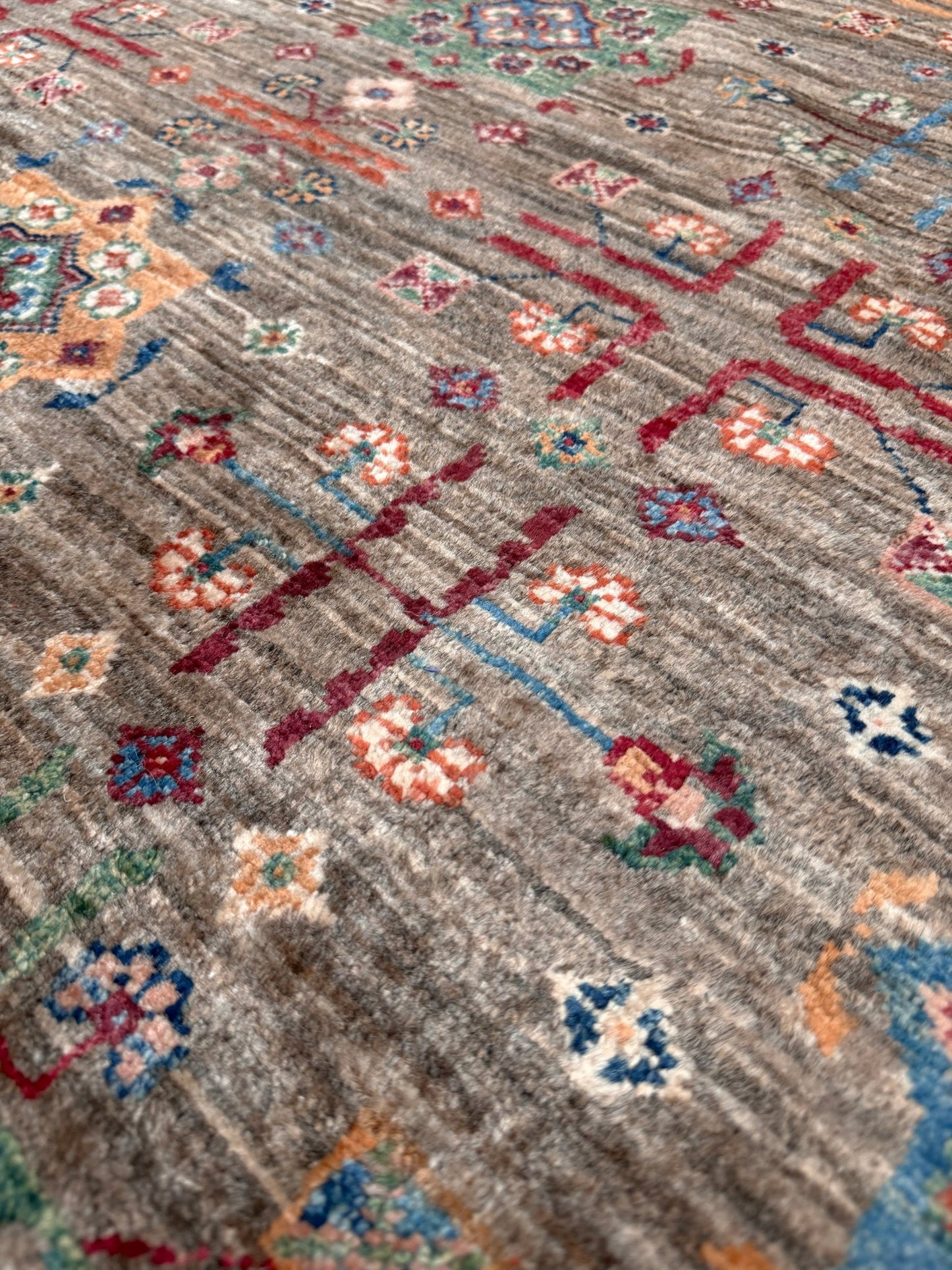 Contemporary Bilcik Turkmen 7x10 rug with dusted olive taupe field, colorful tribal motifs, decorative tassels, handmade Ghazni wool area rug from Indigo Rugs Burlingame Bay Area.