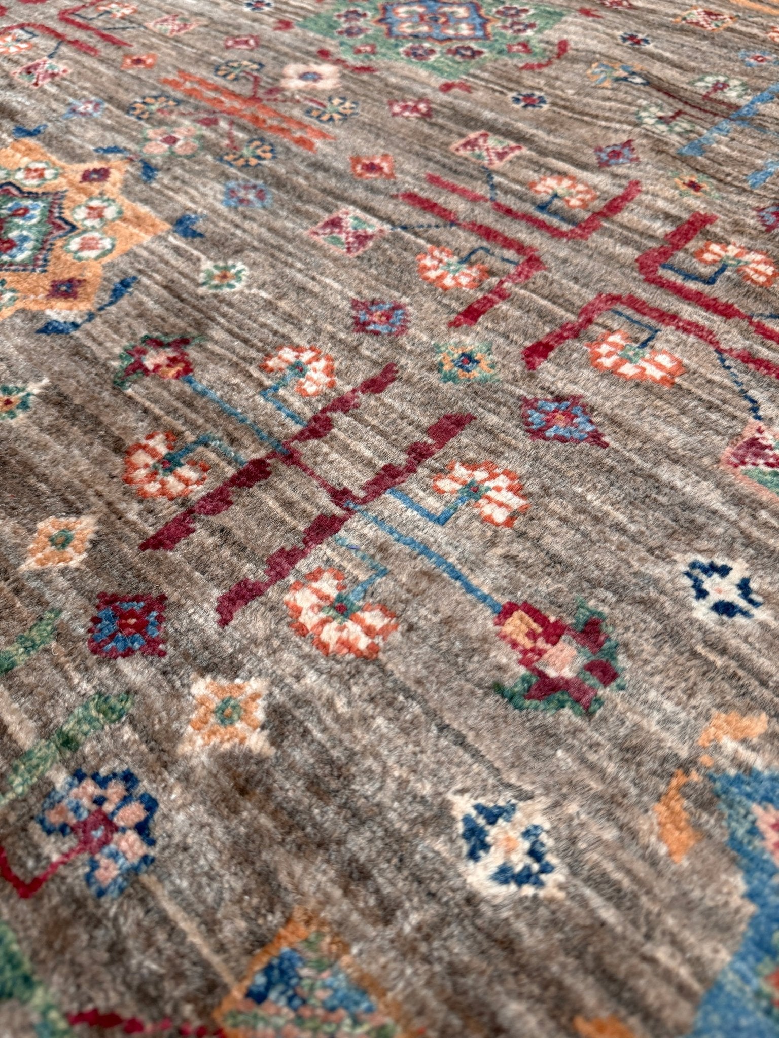 Contemporary Bilcik Turkmen 7x10 rug with dusted olive taupe field, colorful tribal motifs, decorative tassels, handmade Ghazni wool area rug from Indigo Rugs Burlingame Bay Area.