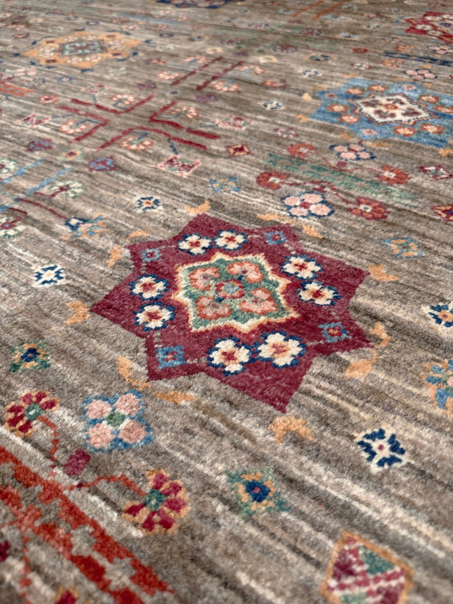Contemporary Bilcik Turkmen 7x10 rug with dusted olive taupe field, colorful tribal motifs, decorative tassels, handmade Ghazni wool area rug from Indigo Rugs Burlingame Bay Area.
