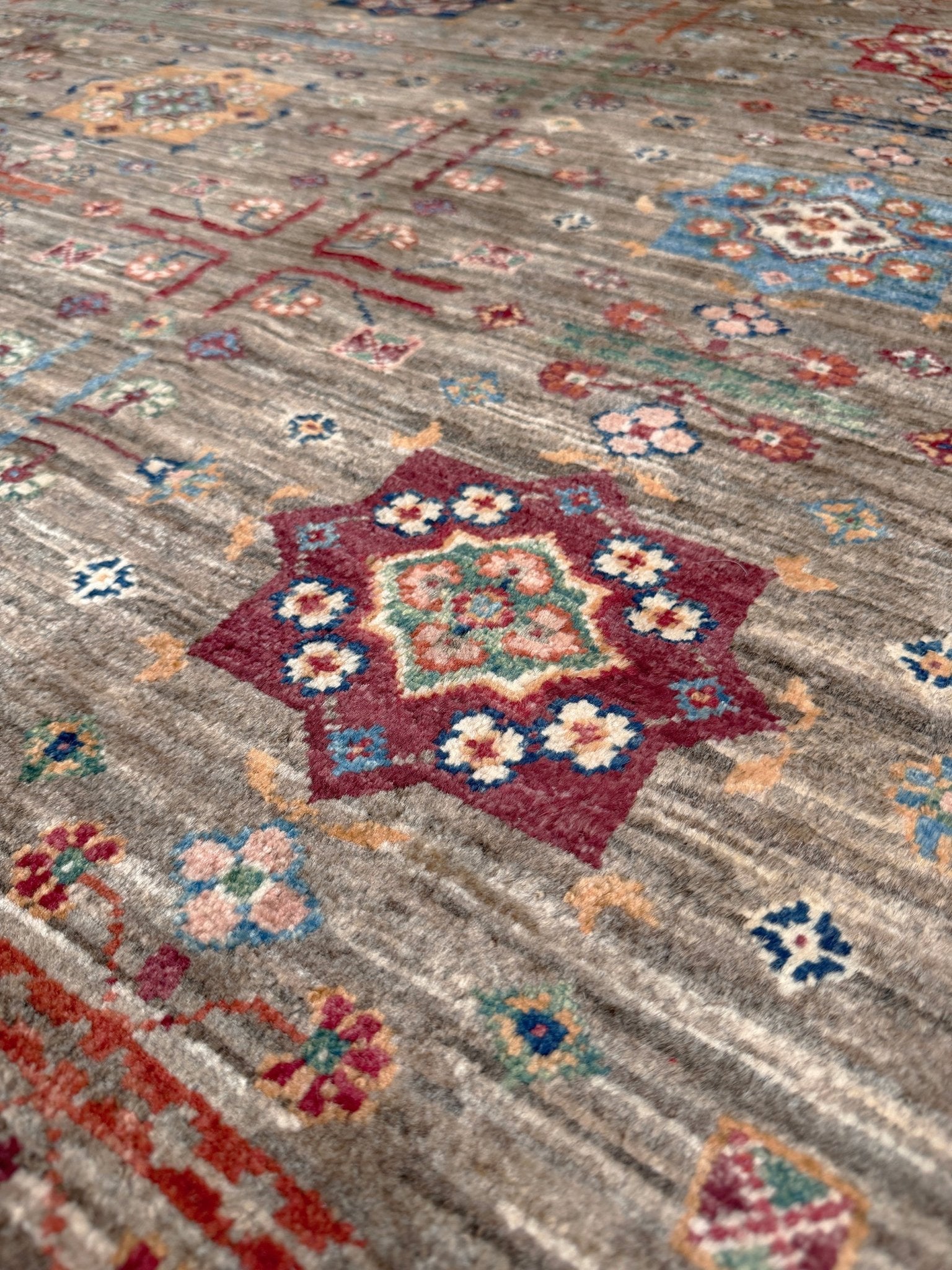 Contemporary Bilcik Turkmen 7x10 rug with dusted olive taupe field, colorful tribal motifs, decorative tassels, handmade Ghazni wool area rug from Indigo Rugs Burlingame Bay Area.