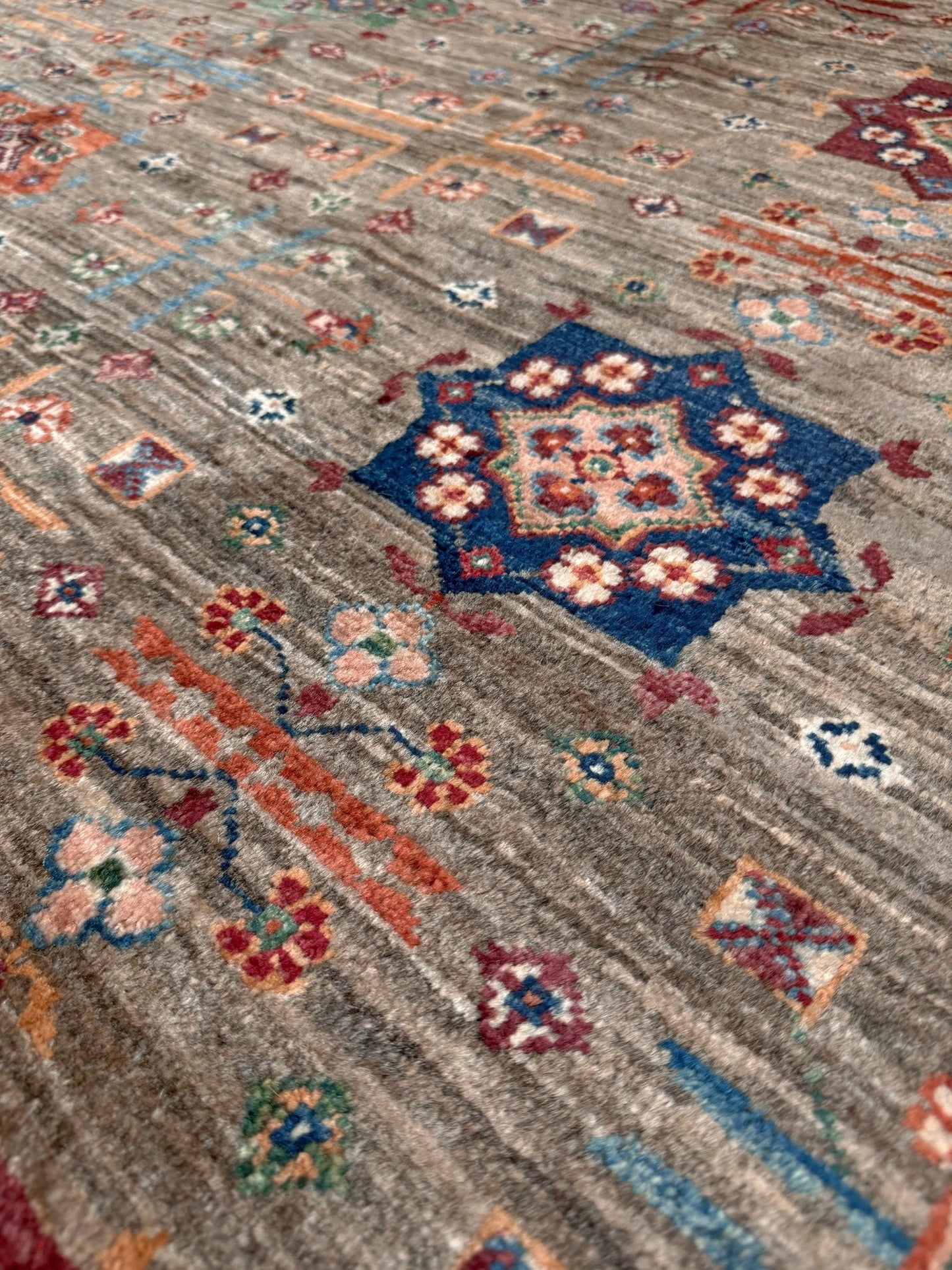 Contemporary Bilcik Turkmen 7x10 rug with dusted olive taupe field, colorful tribal motifs, decorative tassels, handmade Ghazni wool area rug from Indigo Rugs Burlingame Bay Area.