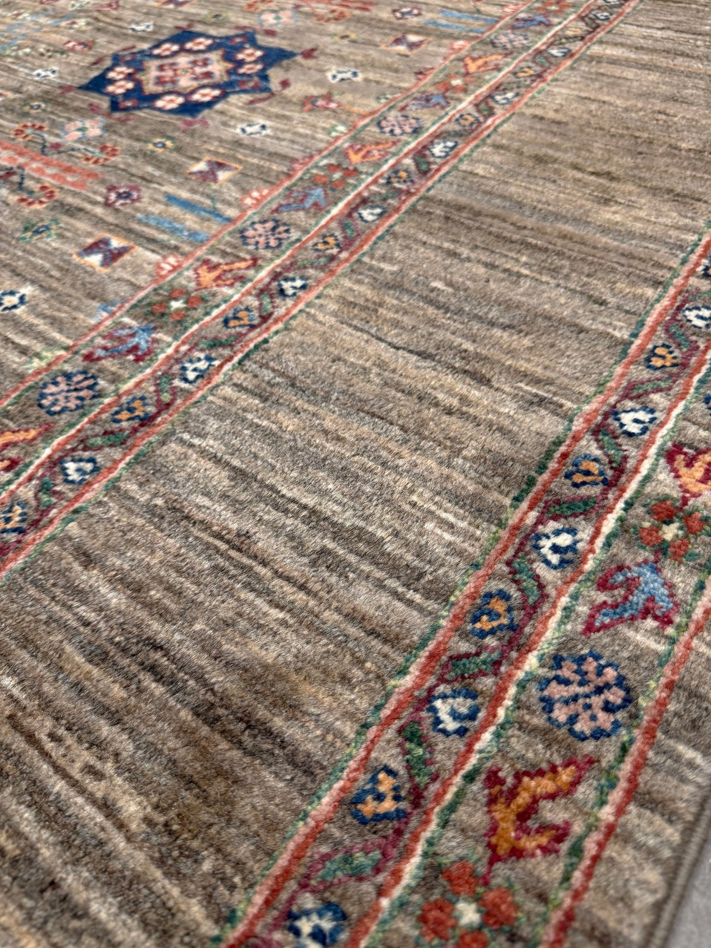 Contemporary Bilcik Turkmen 7x10 rug with dusted olive taupe field, colorful tribal motifs, decorative tassels, handmade Ghazni wool area rug from Indigo Rugs Burlingame Bay Area.