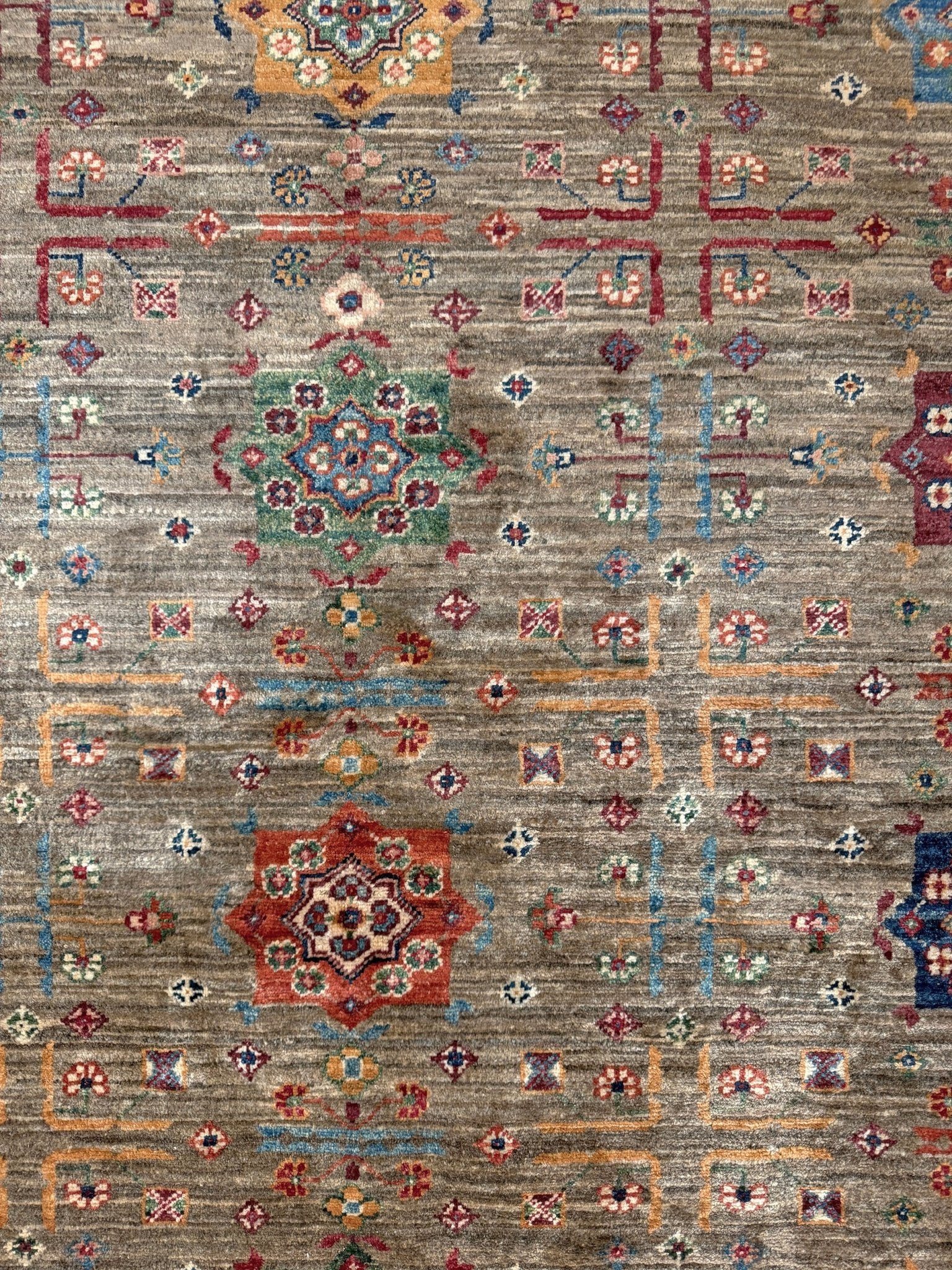 Contemporary Bilcik Turkmen 7x10 rug with dusted olive taupe field, colorful tribal motifs, decorative tassels, handmade Ghazni wool area rug from Indigo Rugs Burlingame Bay Area.