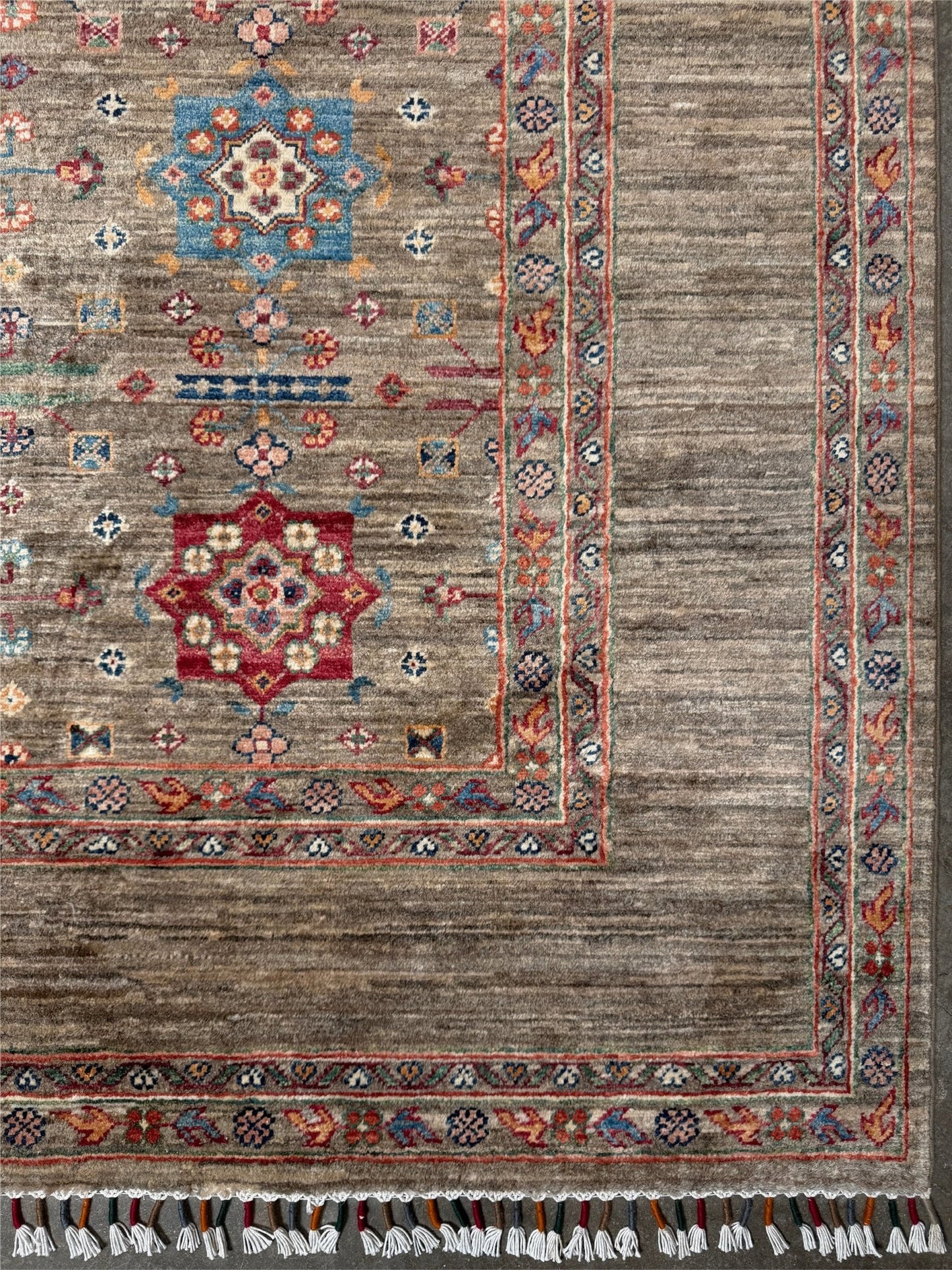 Contemporary Bilcik Turkmen 7x10 rug with dusted olive taupe field, colorful tribal motifs, decorative tassels, handmade Ghazni wool area rug from Indigo Rugs Burlingame Bay Area.