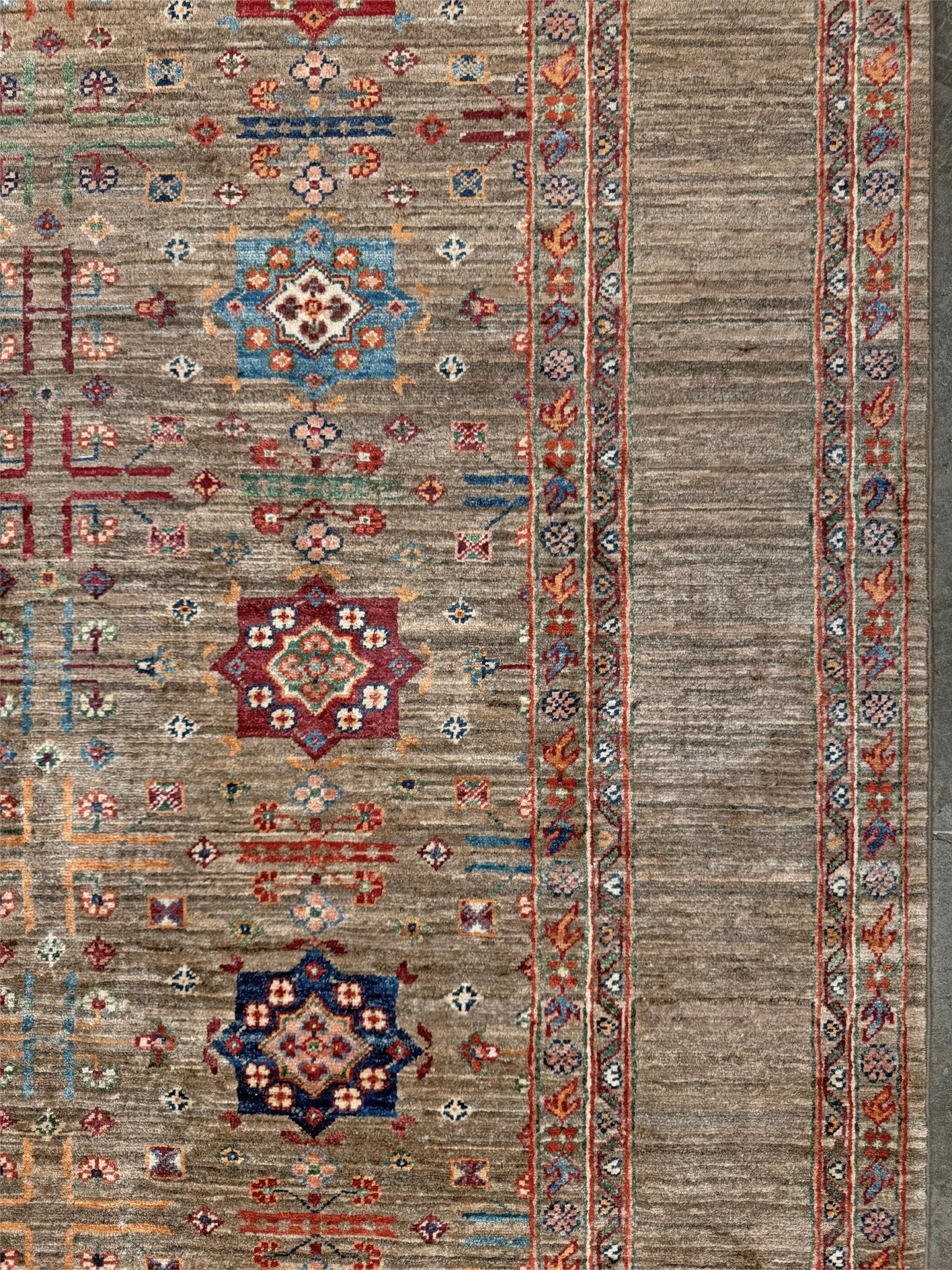 Contemporary Bilcik Turkmen 7x10 rug with dusted olive taupe field, colorful tribal motifs, decorative tassels, handmade Ghazni wool area rug from Indigo Rugs Burlingame Bay Area.