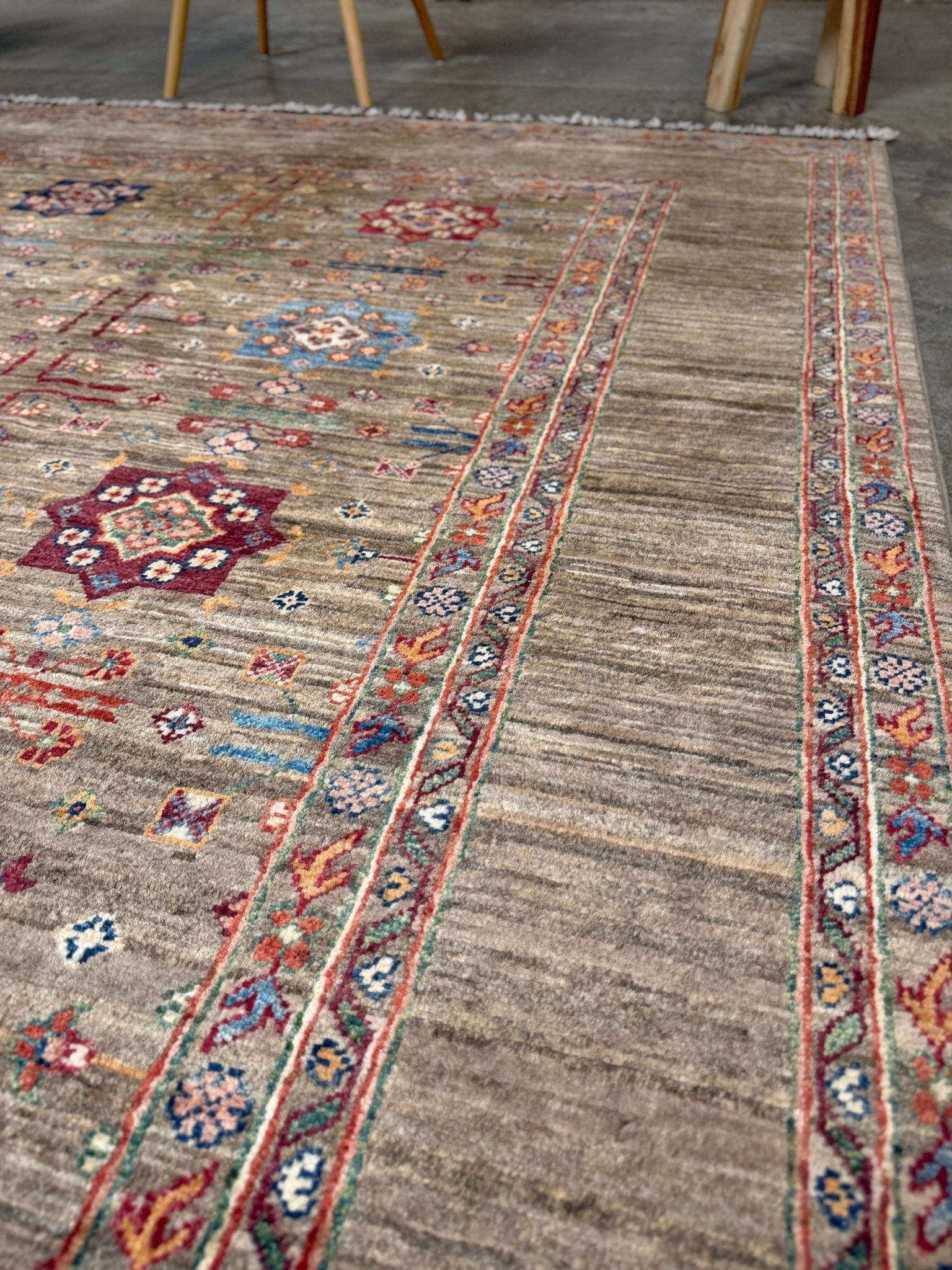 Contemporary Bilcik Turkmen 7x10 rug with dusted olive taupe field, colorful tribal motifs, decorative tassels, handmade Ghazni wool area rug from Indigo Rugs Burlingame Bay Area.