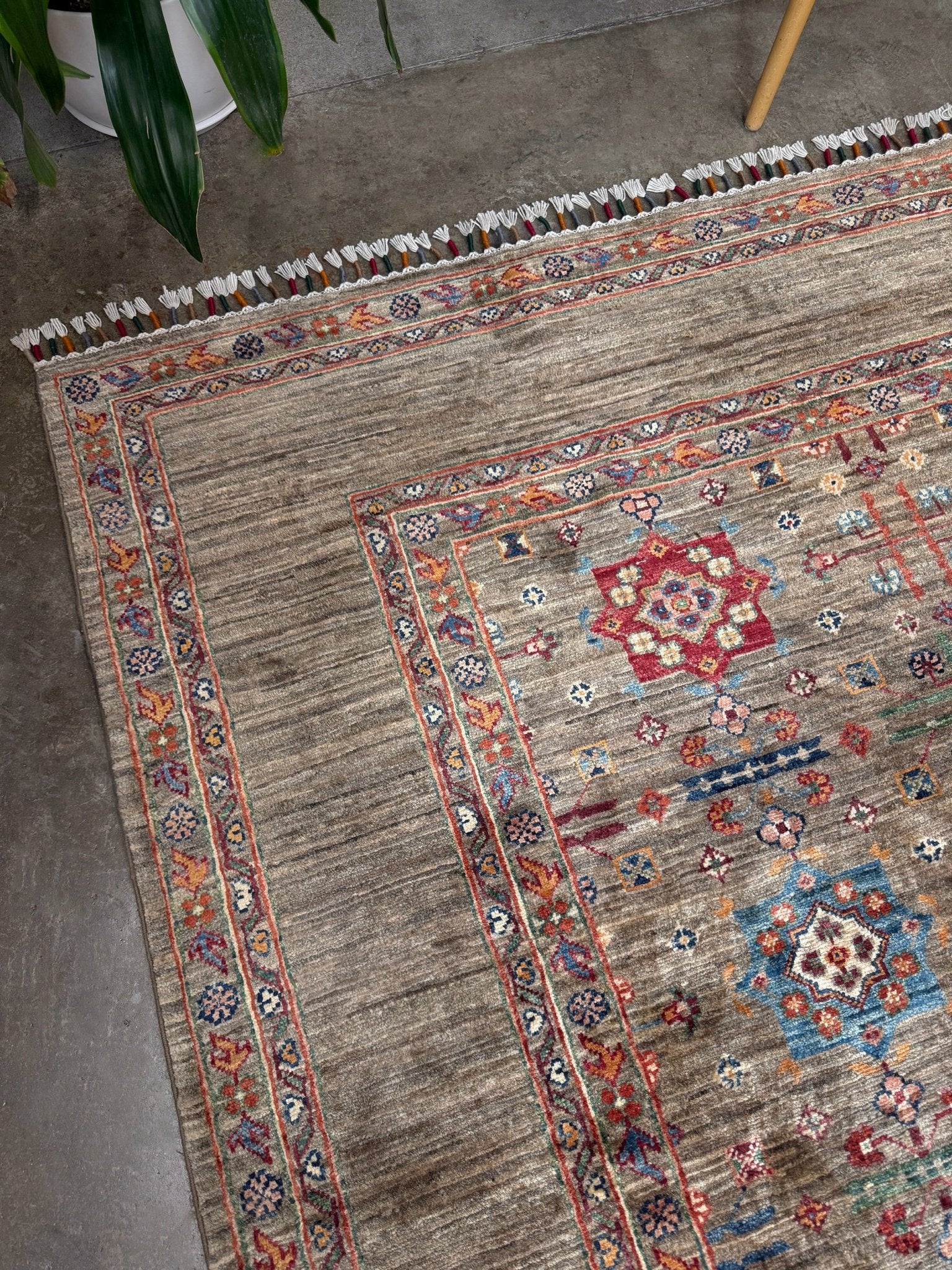 Contemporary Bilcik Turkmen 7x10 rug with dusted olive taupe field, colorful tribal motifs, decorative tassels, handmade Ghazni wool area rug from Indigo Rugs Burlingame Bay Area.