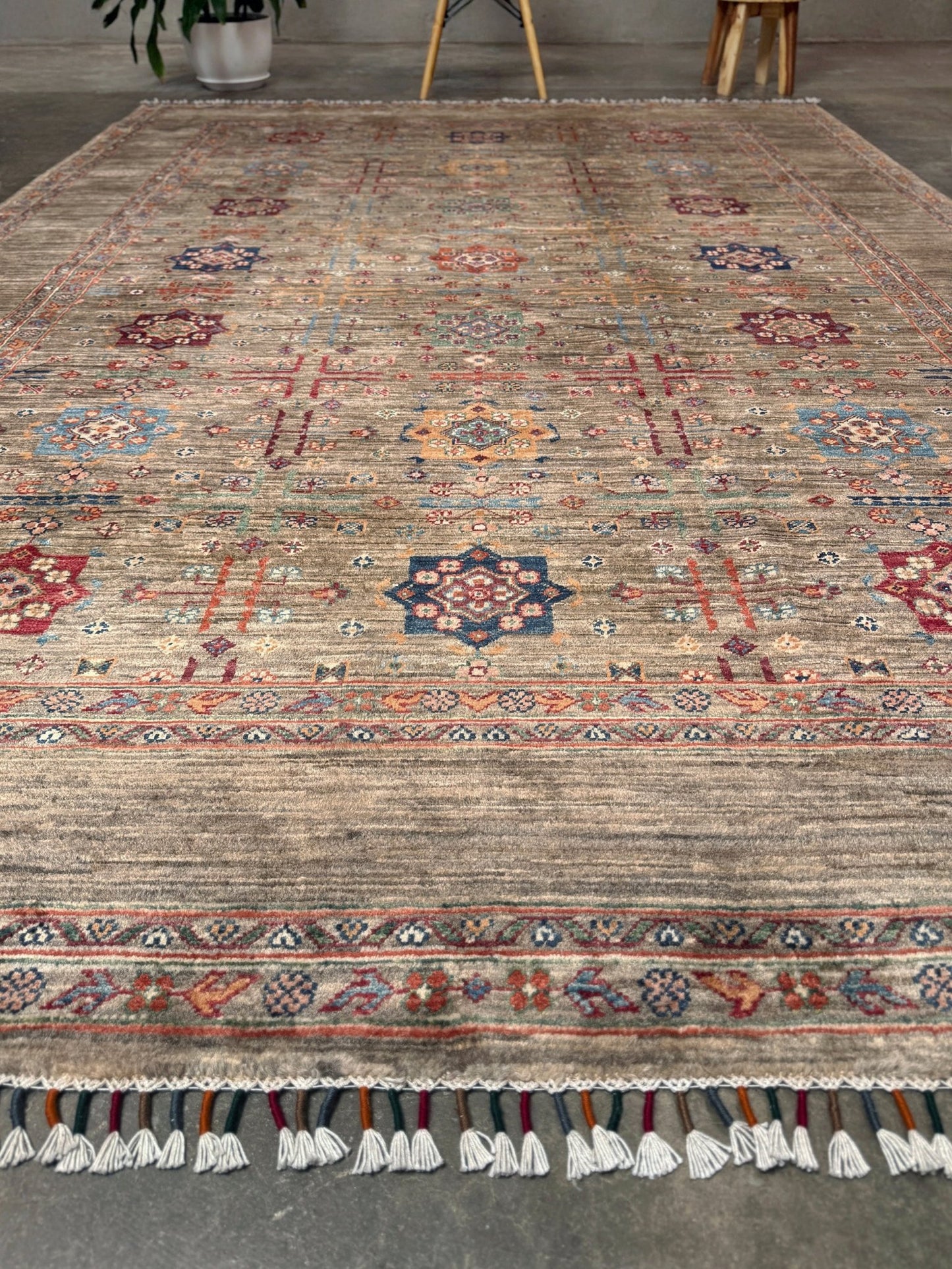 Contemporary Bilcik Turkmen 7x10 rug with dusted olive taupe field, colorful tribal motifs, decorative tassels, handmade Ghazni wool area rug from Indigo Rugs Burlingame Bay Area.