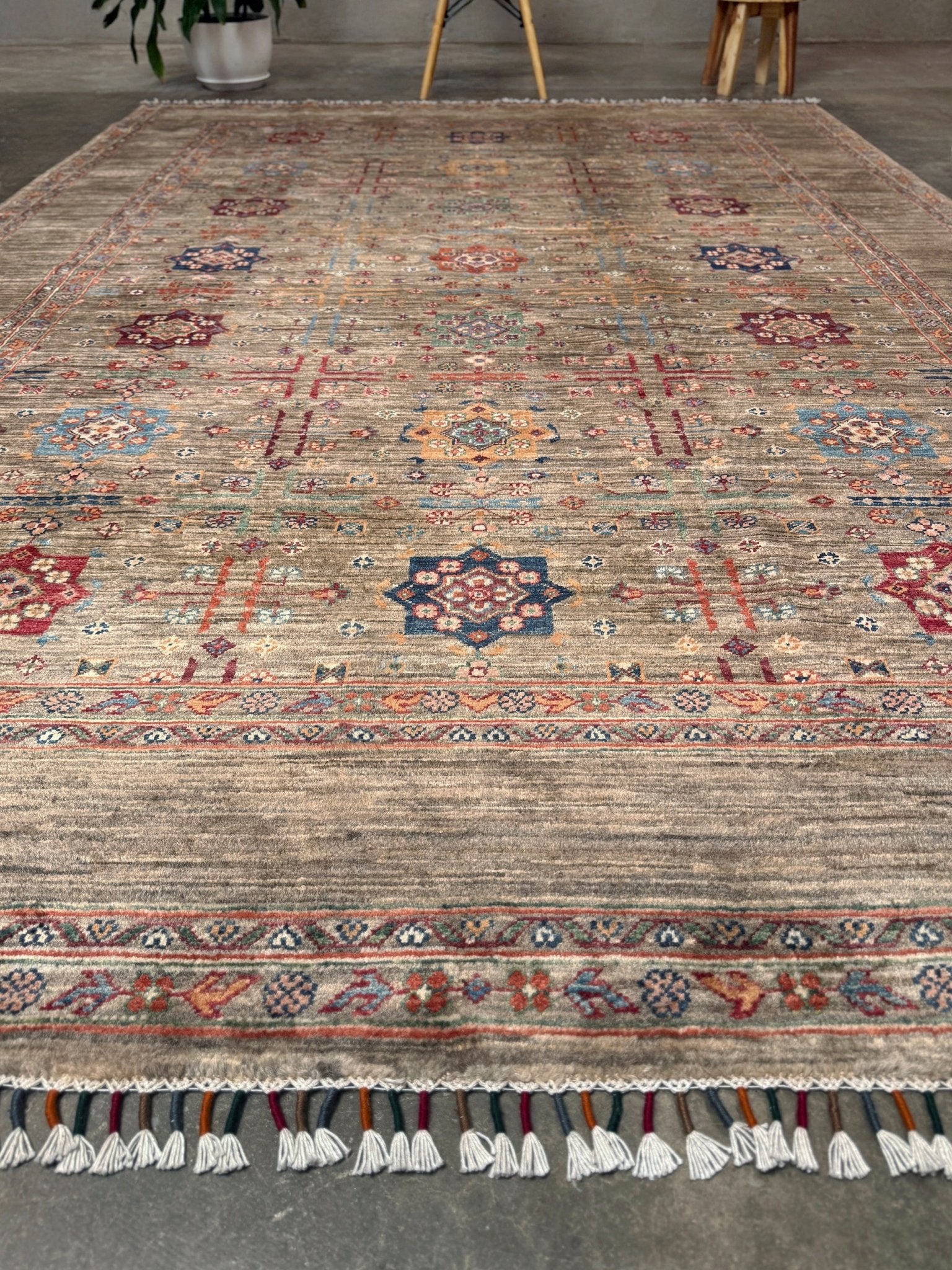 Contemporary Bilcik Turkmen 7x10 rug with dusted olive taupe field, colorful tribal motifs, decorative tassels, handmade Ghazni wool area rug from Indigo Rugs Burlingame Bay Area.