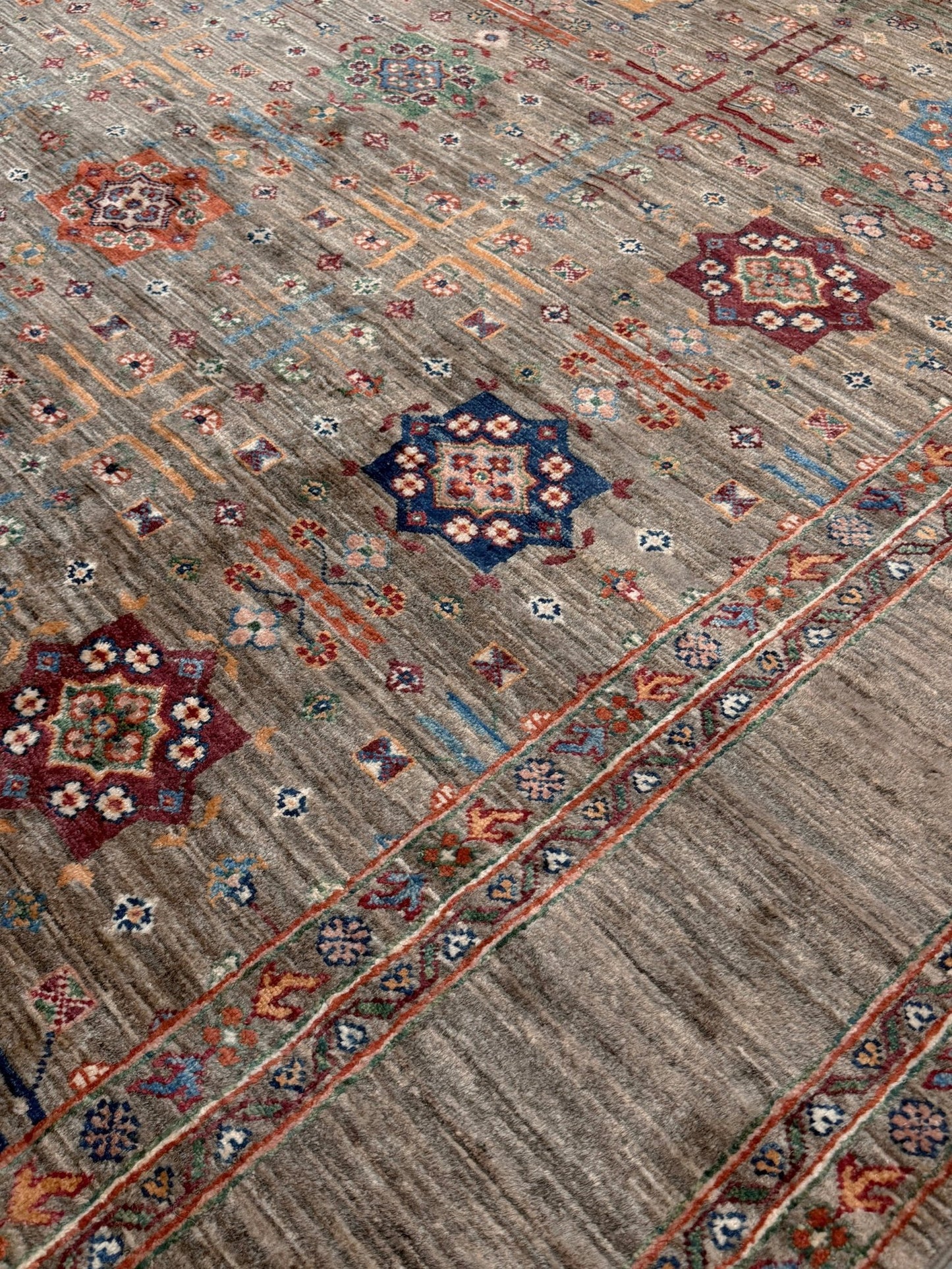 Contemporary Bilcik Turkmen 7x10 rug with dusted olive taupe field, colorful tribal motifs, decorative tassels, handmade Ghazni wool area rug from Indigo Rugs Burlingame Bay Area.