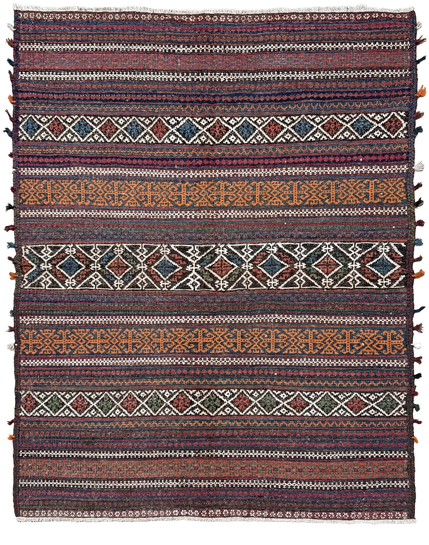 Patterned rug with multicolor stripes and geometric designs on a white background. Vintage Persian tribal kilim rug with geometric horizontal bands, brick red, indigo blue, orange, decorative side tassels, handmade wool flatweave 5x6 from Indigo Rugs Burlingame Bay Area.