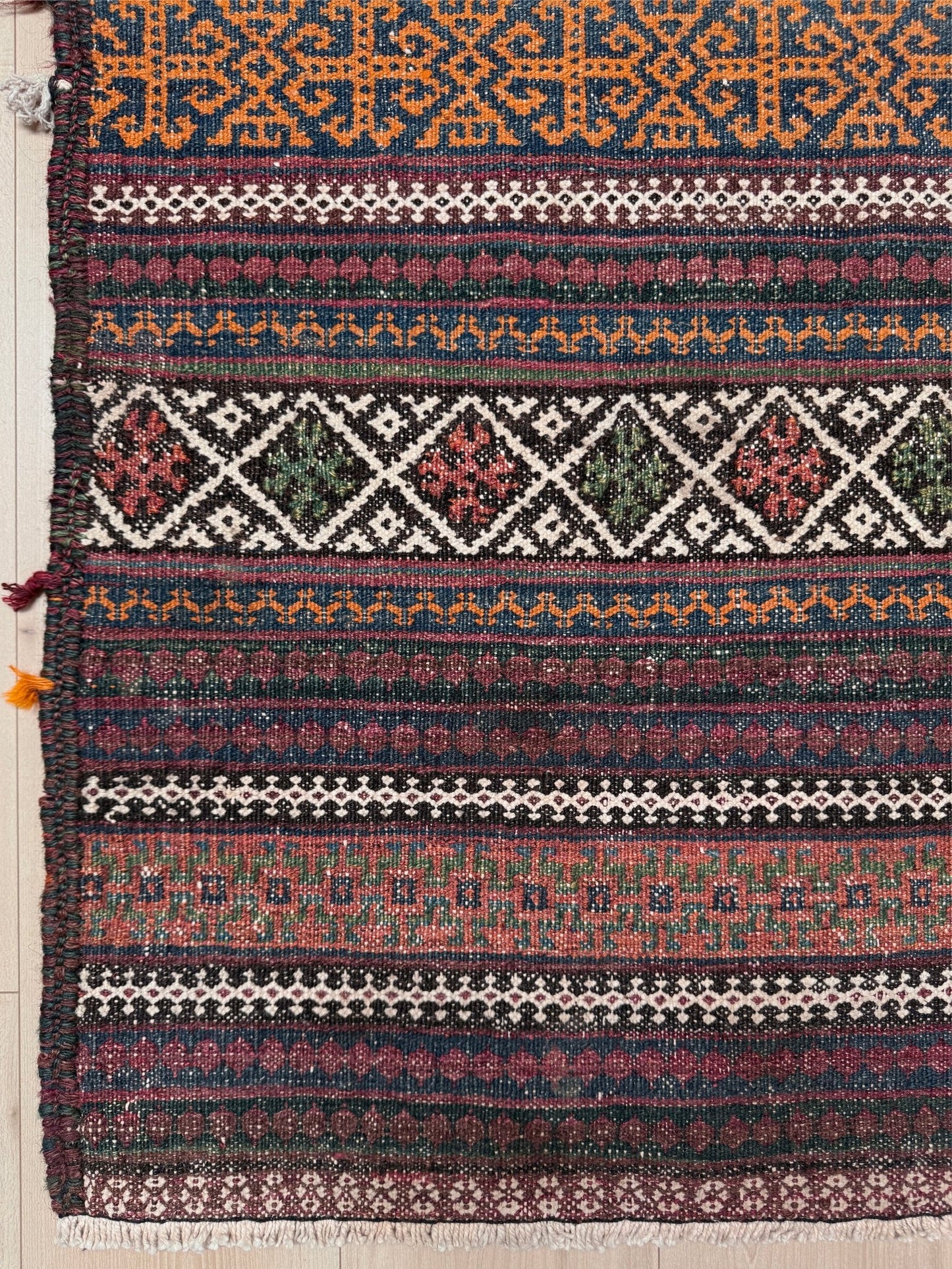 Vintage Persian tribal kilim rug with geometric horizontal bands, brick red, indigo blue, orange, decorative side tassels, handmade wool flatweave 5x6 from Indigo Rugs Burlingame Bay Area.
