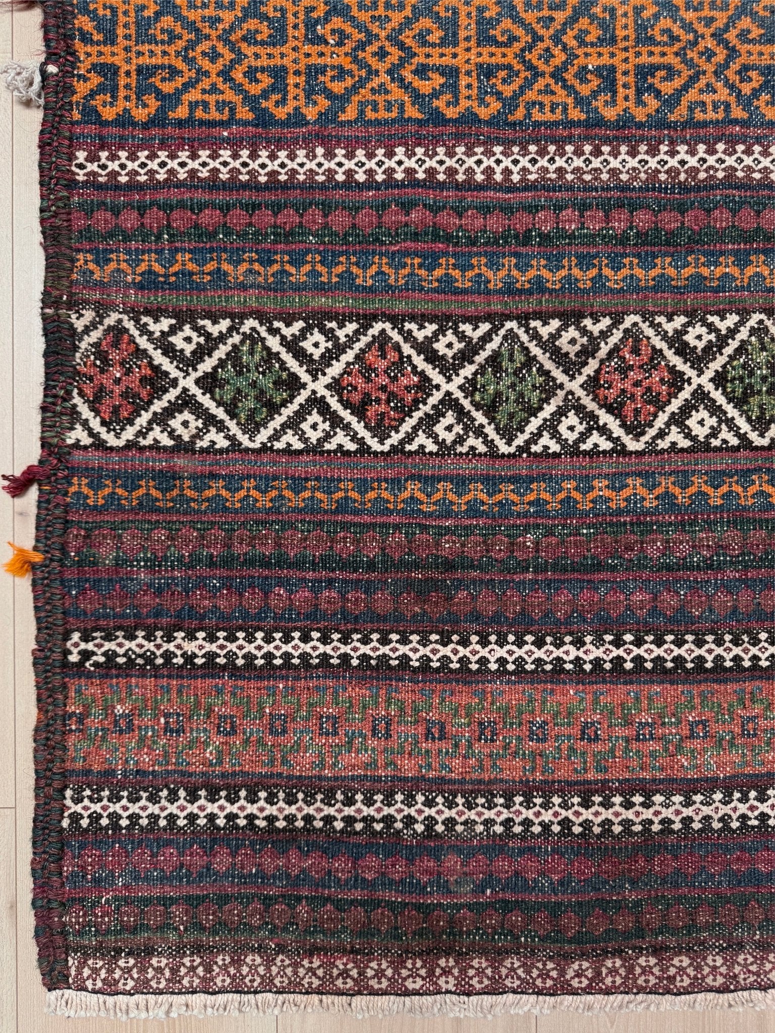 Vintage Persian tribal kilim rug with geometric horizontal bands, brick red, indigo blue, orange, decorative side tassels, handmade wool flatweave 5x6 from Indigo Rugs Burlingame Bay Area.