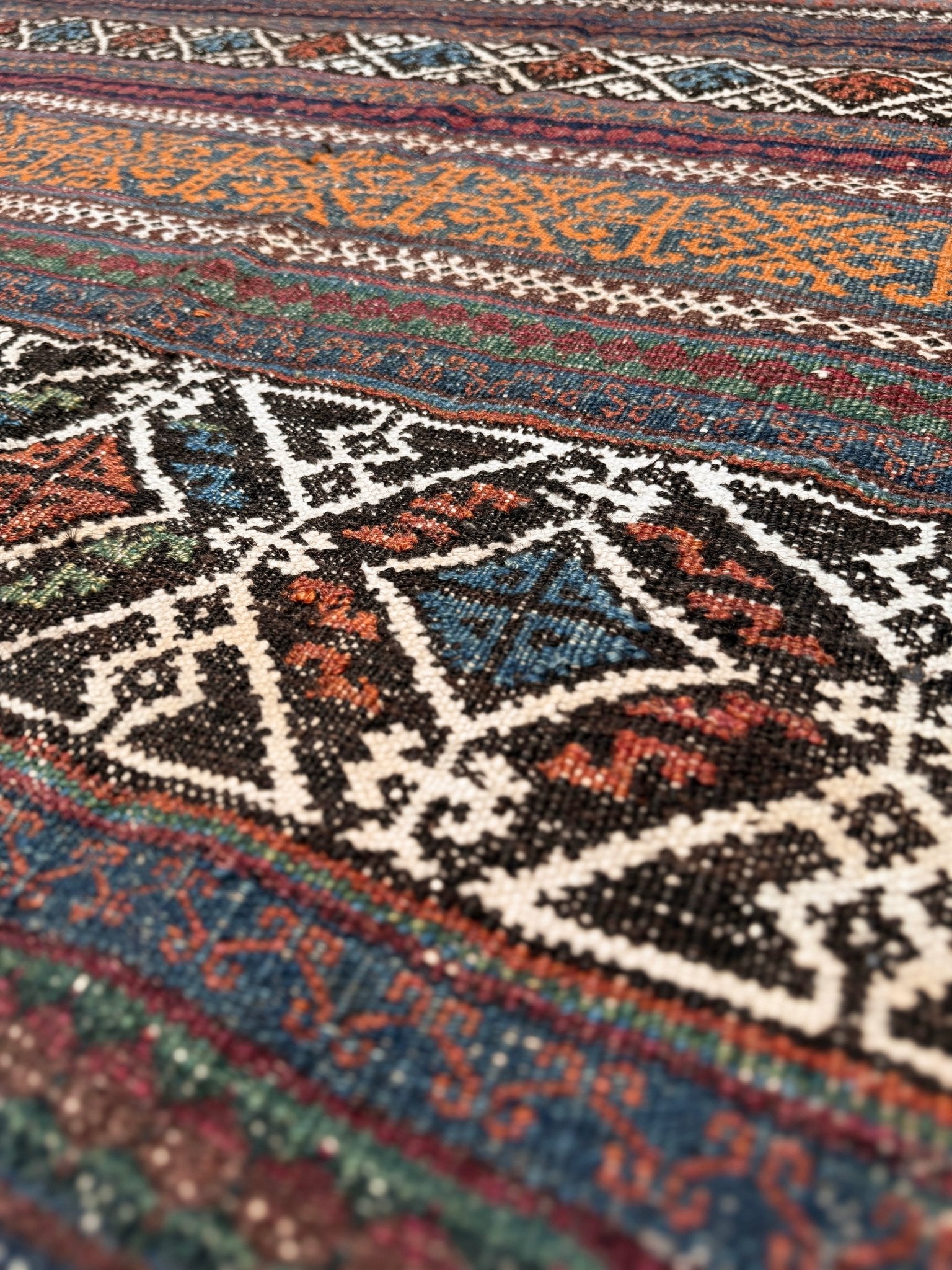 Vintage Persian tribal kilim rug with geometric horizontal bands, brick red, indigo blue, orange, decorative side tassels, handmade wool flatweave 5x6 from Indigo Rugs Burlingame Bay Area.